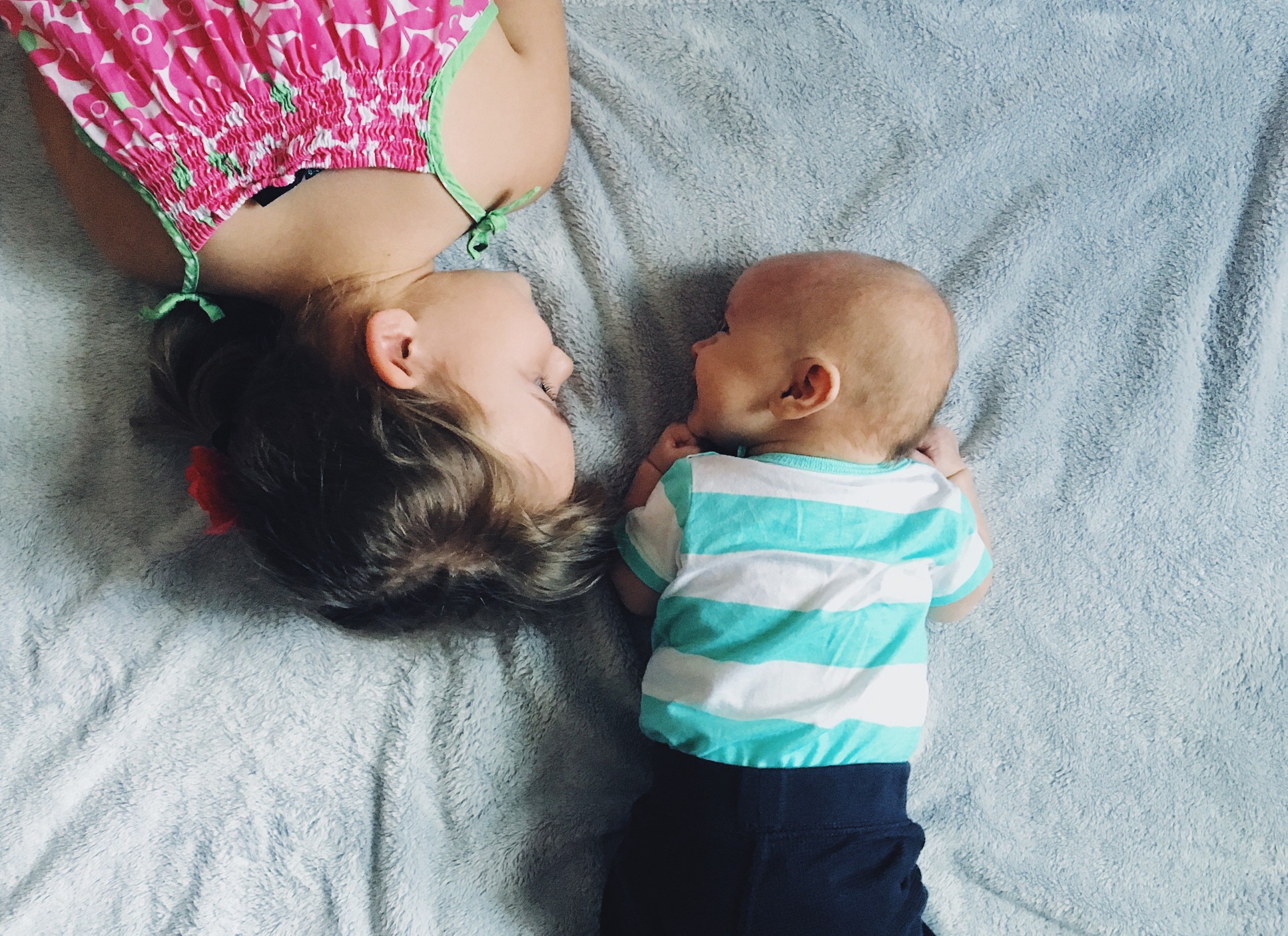 big-sister-laying-with-smiling-baby-brother-on-a-gray-blanket-during-tummy-time_t20_kRabYr.jpg