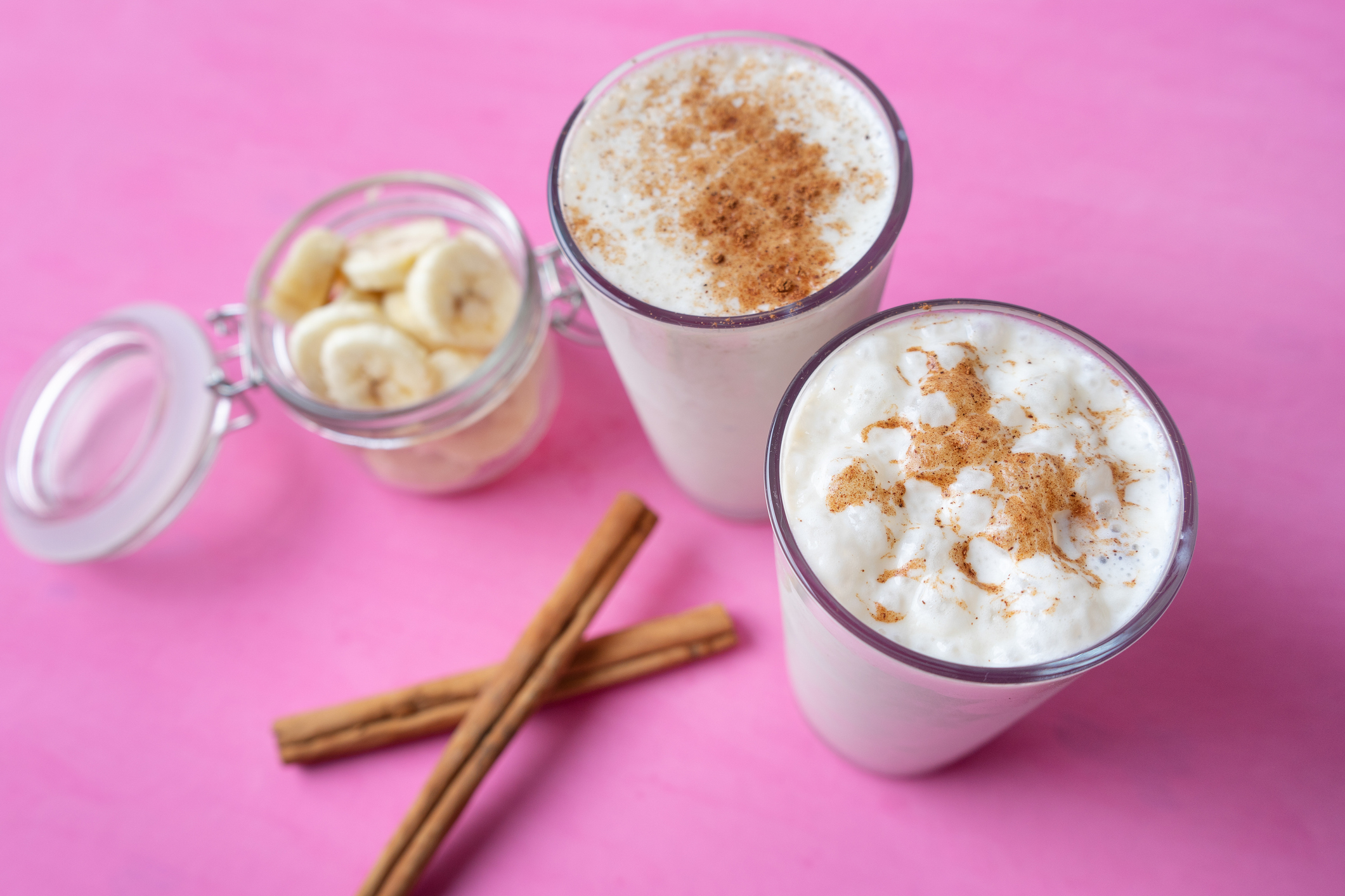 Banana smothie or milkshake with cinnamon on pink  background