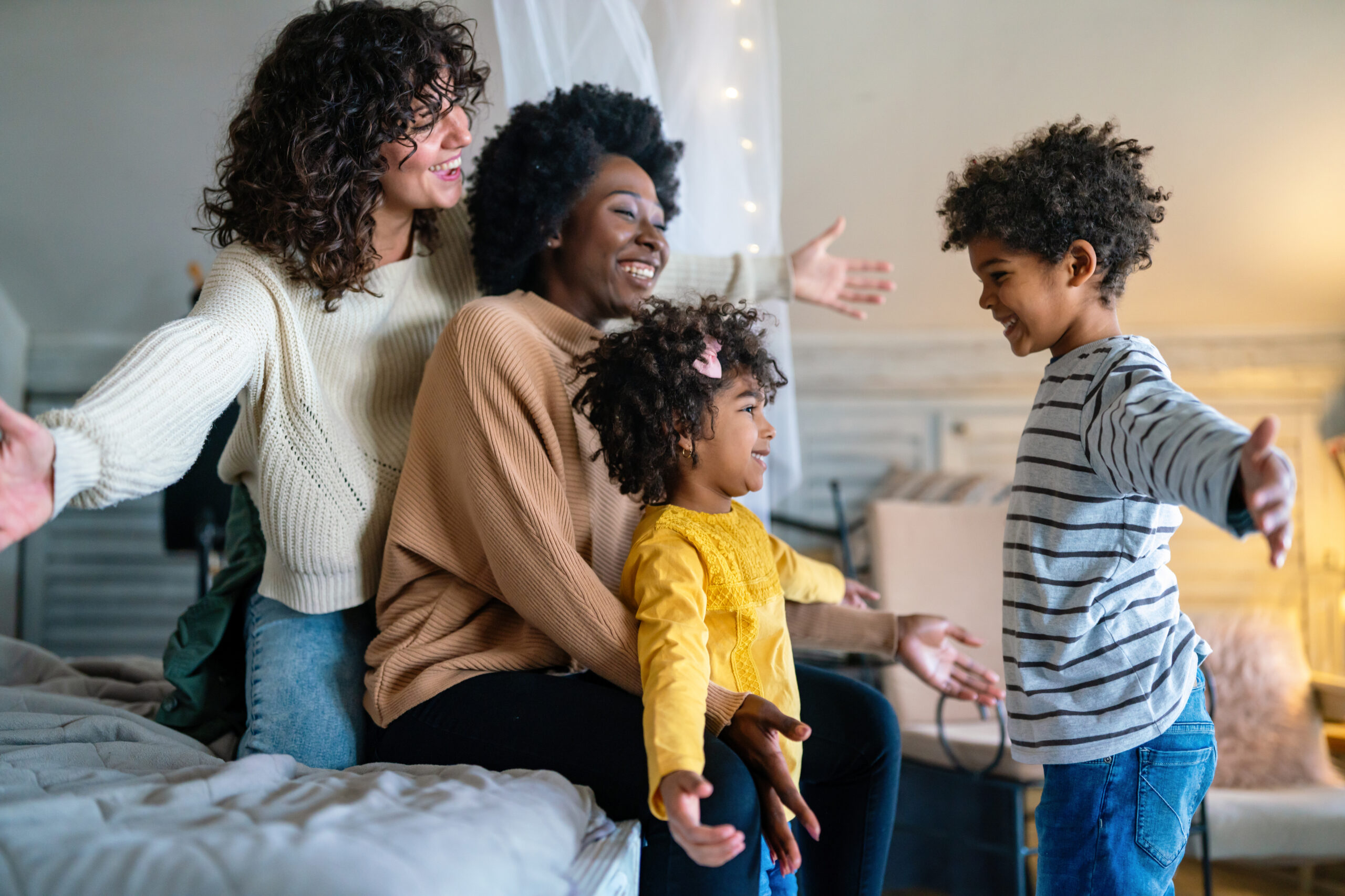 Happy multiethnic family. Smiling gay women couple spending time together with children at home.