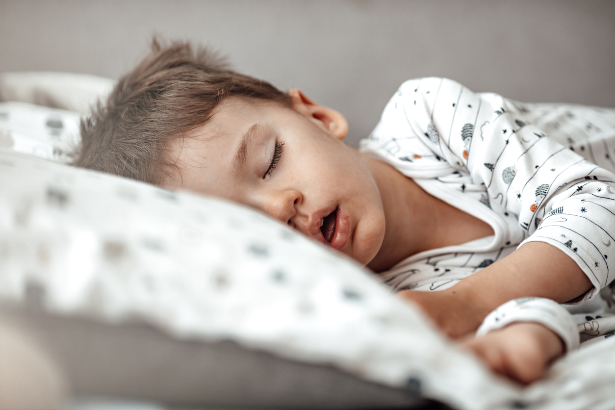 Little blond boy sleeping in his bed.