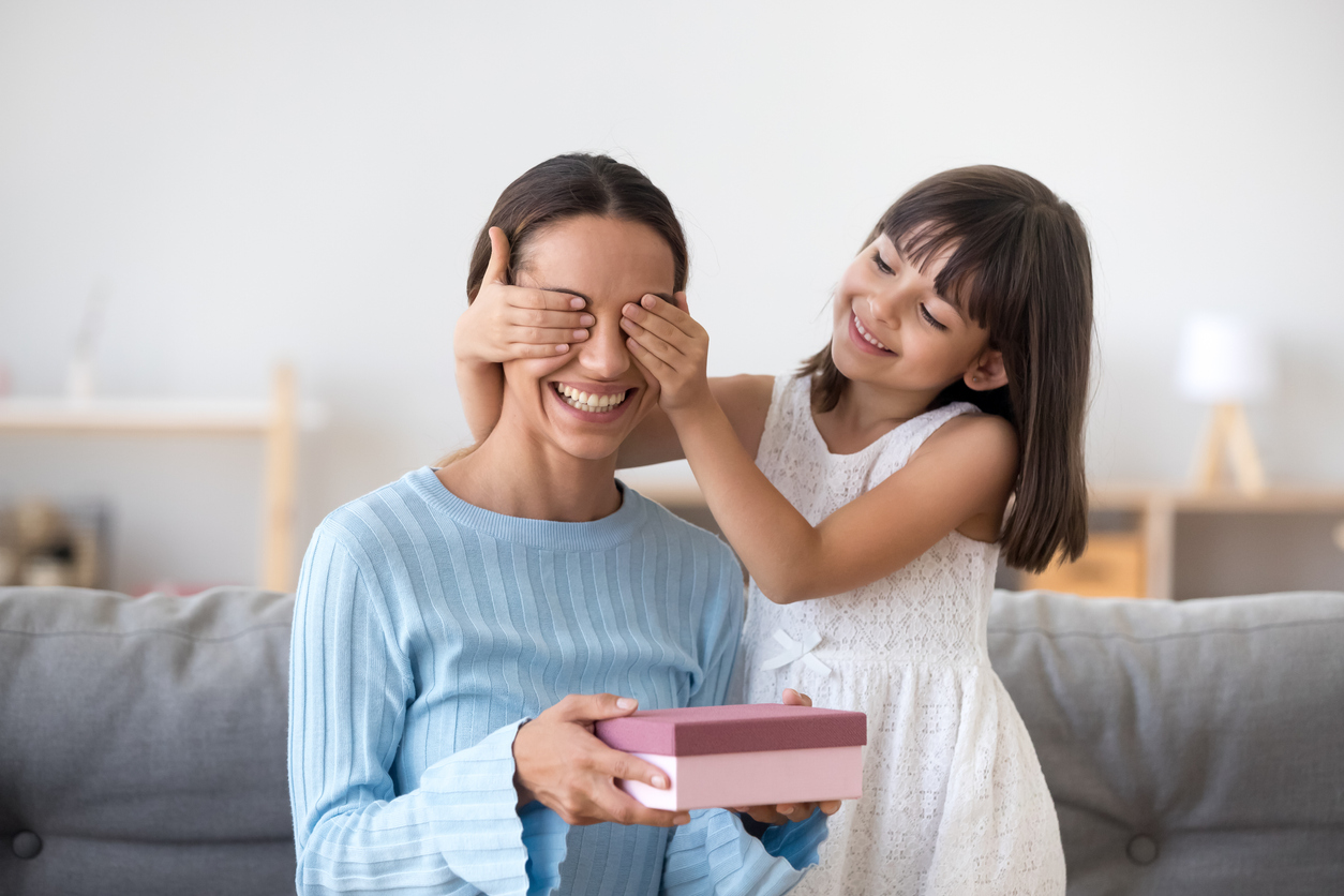 Smiling child daughter closing mom eyes congratulating with mothers day