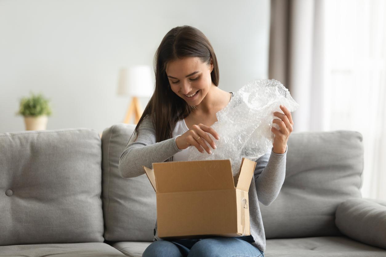 Happy young woman customer open parcel box sit on sofa