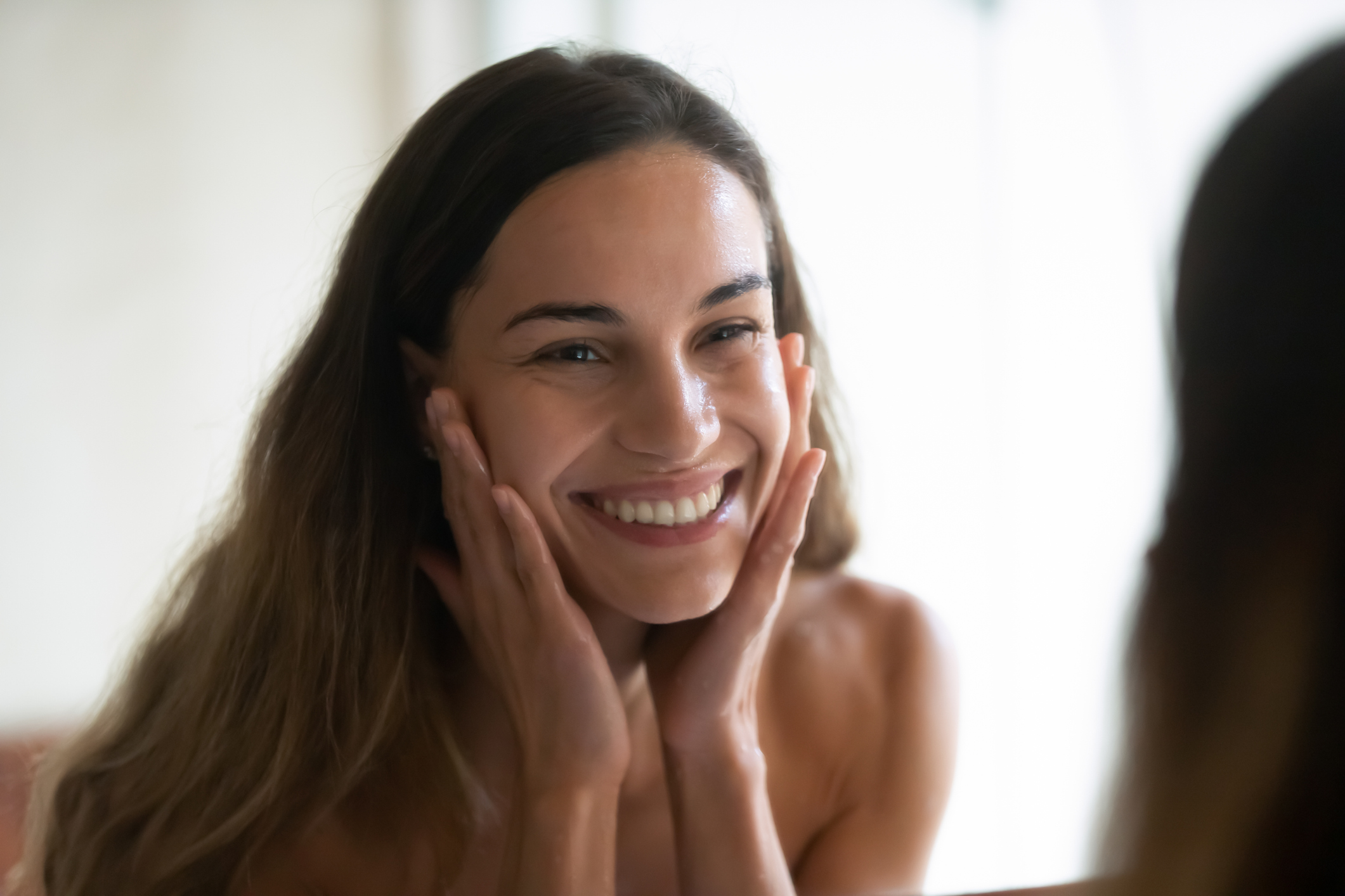 Smiling young woman look in mirror washing face