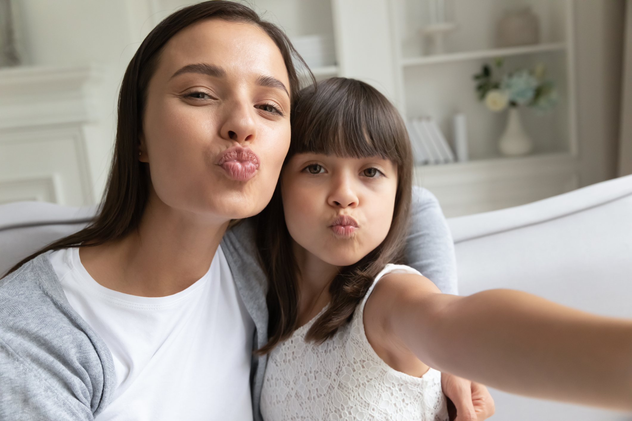 Funny young mom and preschooler daughter make selfie together