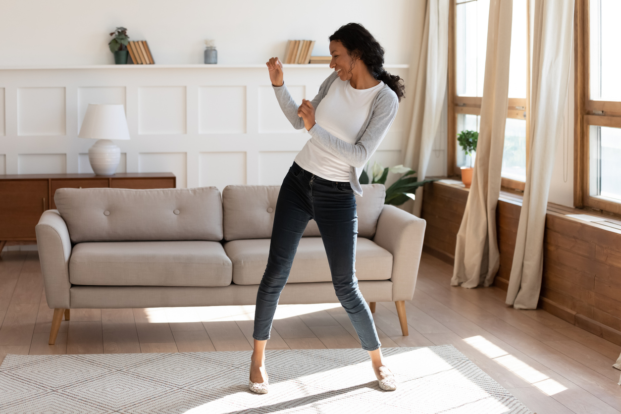 Overjoyed african American woman dancing alone at home