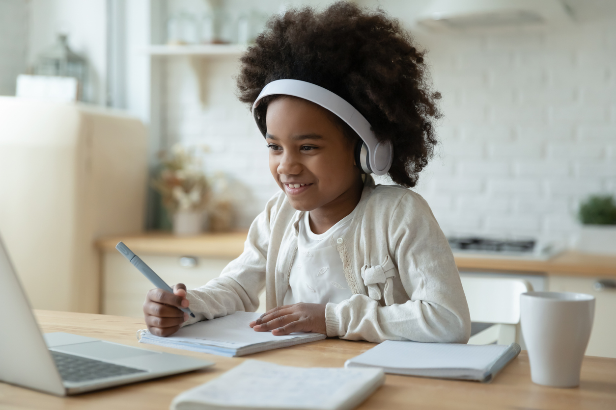 Smiling biracial girl watch video on laptop at home