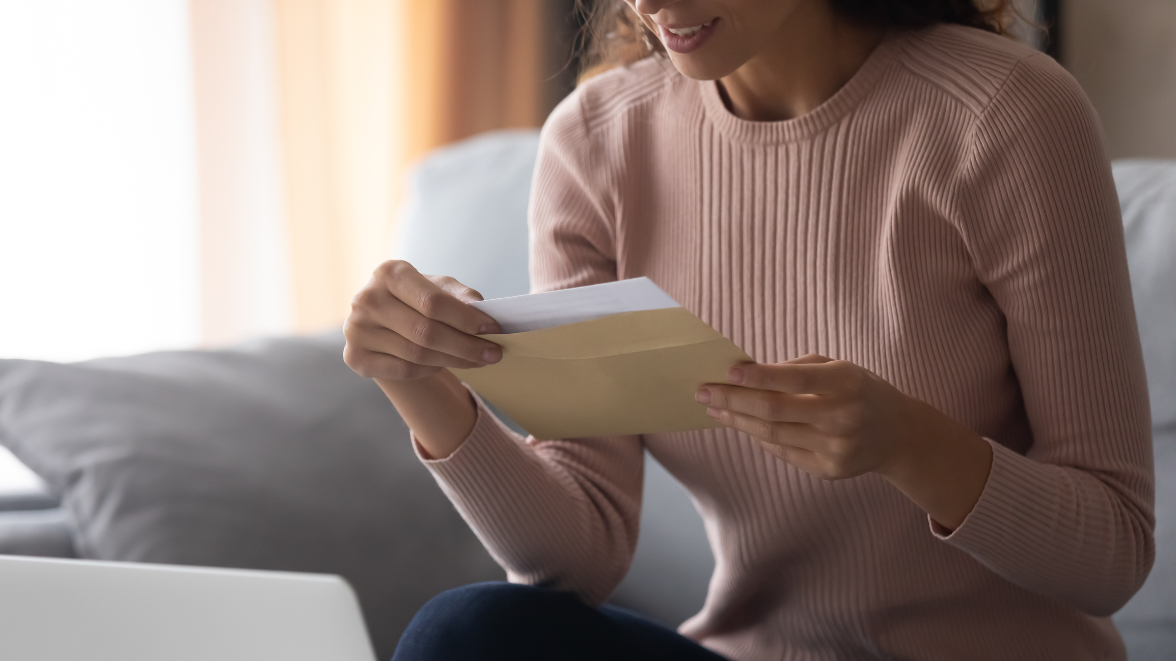 Smiling young woman holding envelope with paper letter.