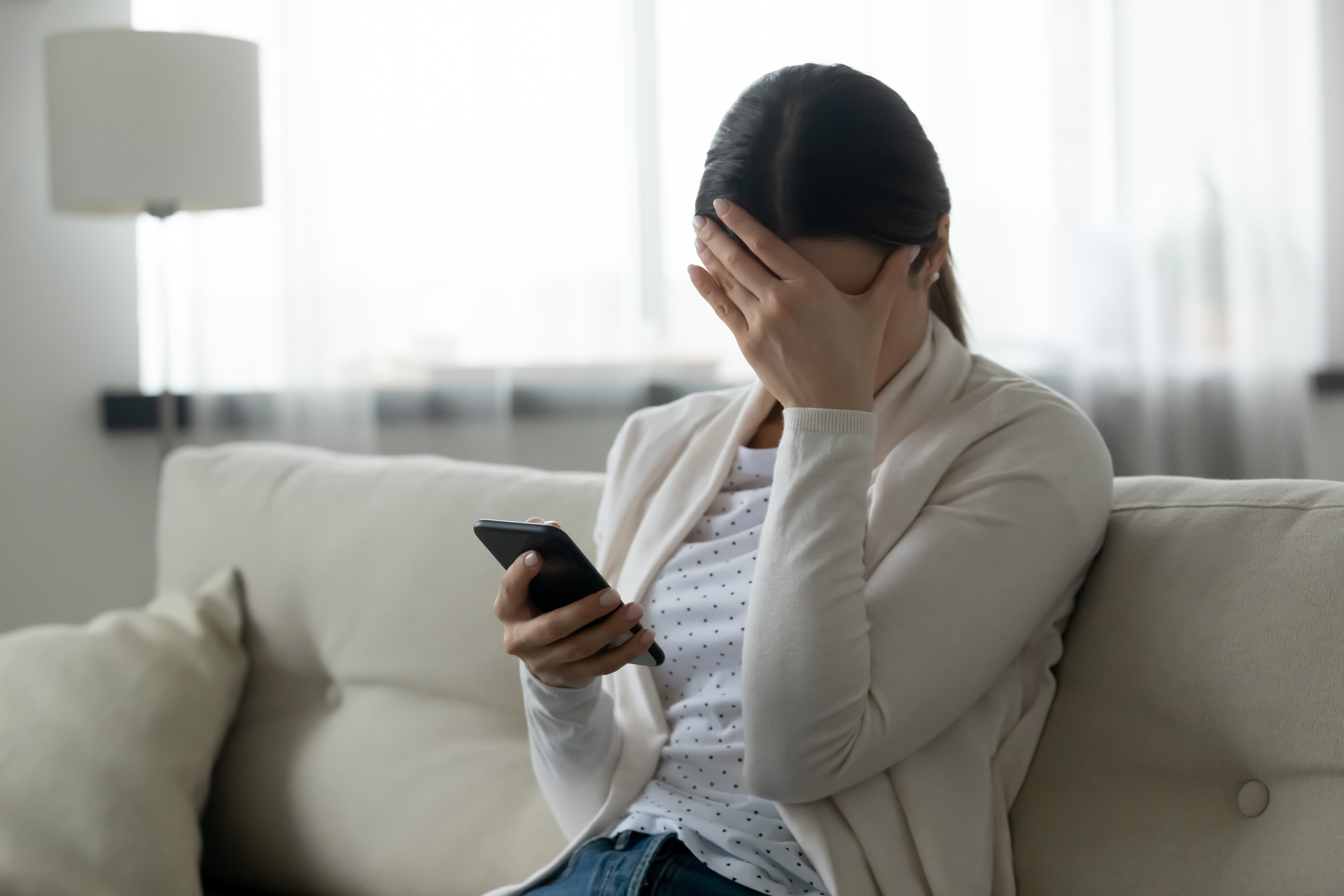 Stressed woman holding smartphone feels humiliated, cyberbullying concept