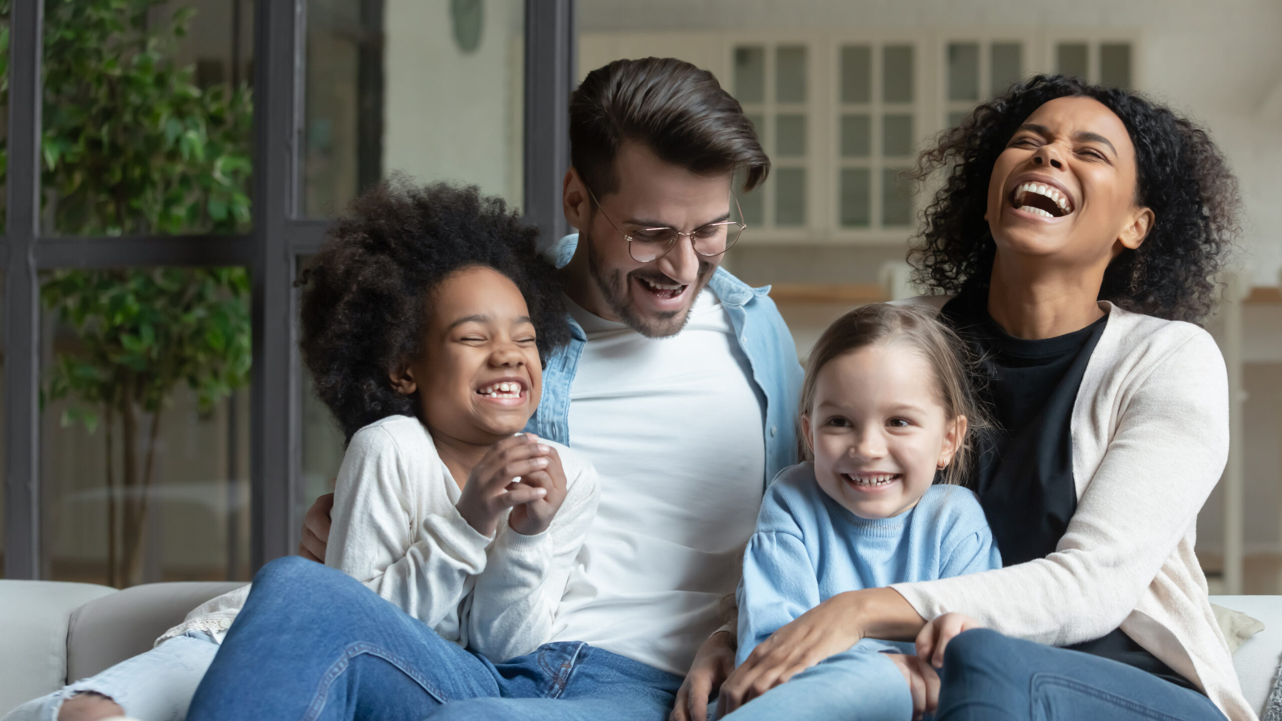 Happy multiracial family with little daughters relax at home