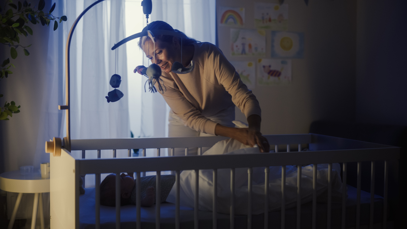 Authentic Shot of a Mother Soothing and Cuddling a Newborn Baby Boy in Child Crib. Caucasian Neonate Toddler at Home in Kids Bedroom. Concept of Childhood, New Llife and Parenthood.