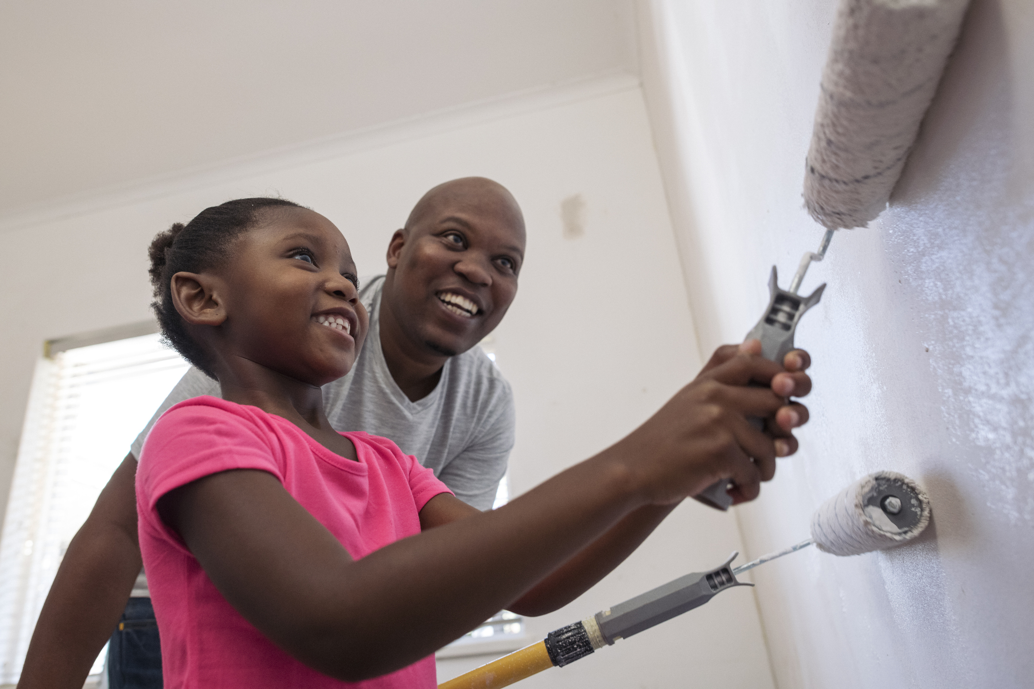 Big smiles as daughter helps father paint close up low angle view