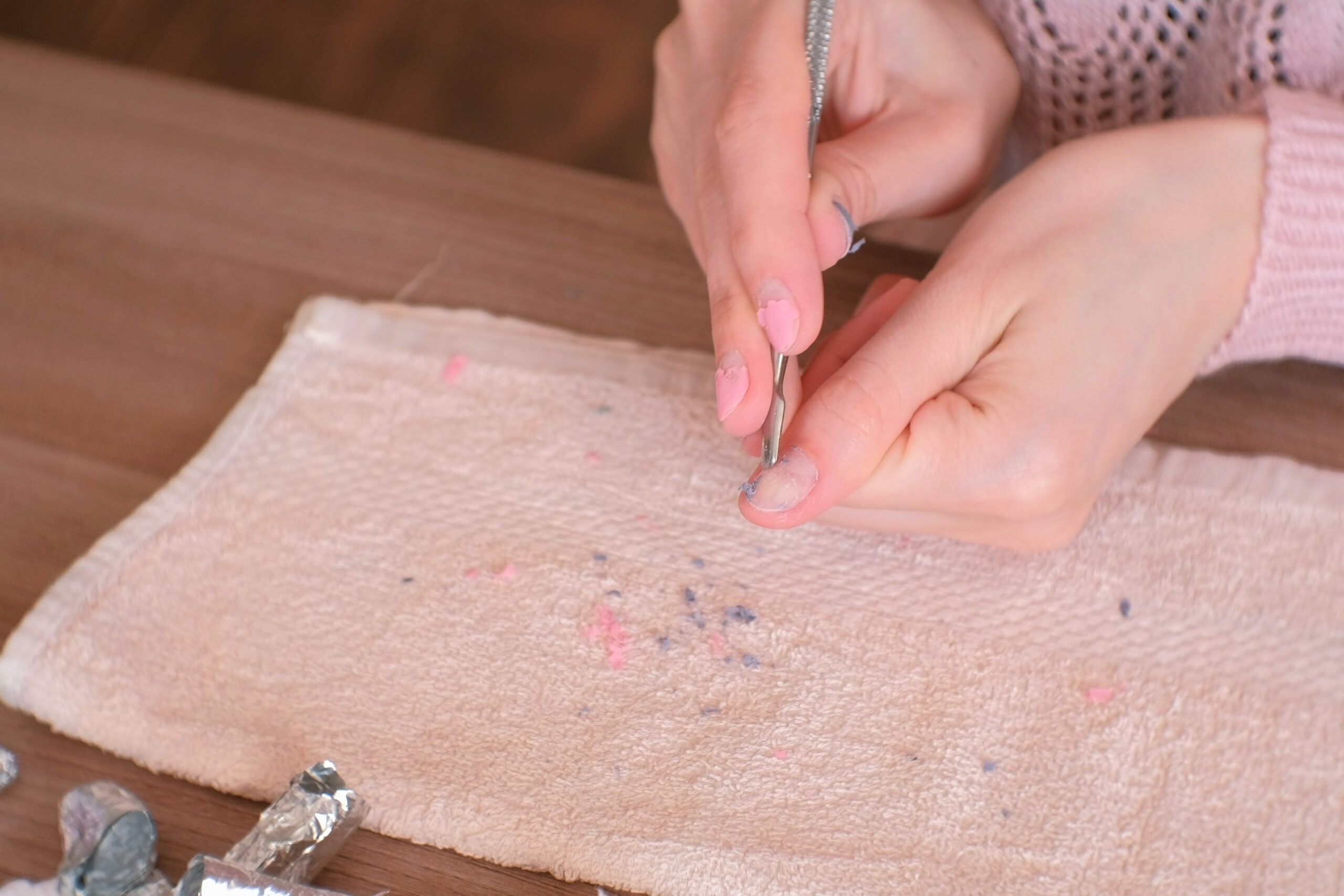 Removing gel Polish from nails. Woman removes shellac from nails with pusher. Close-up hand.