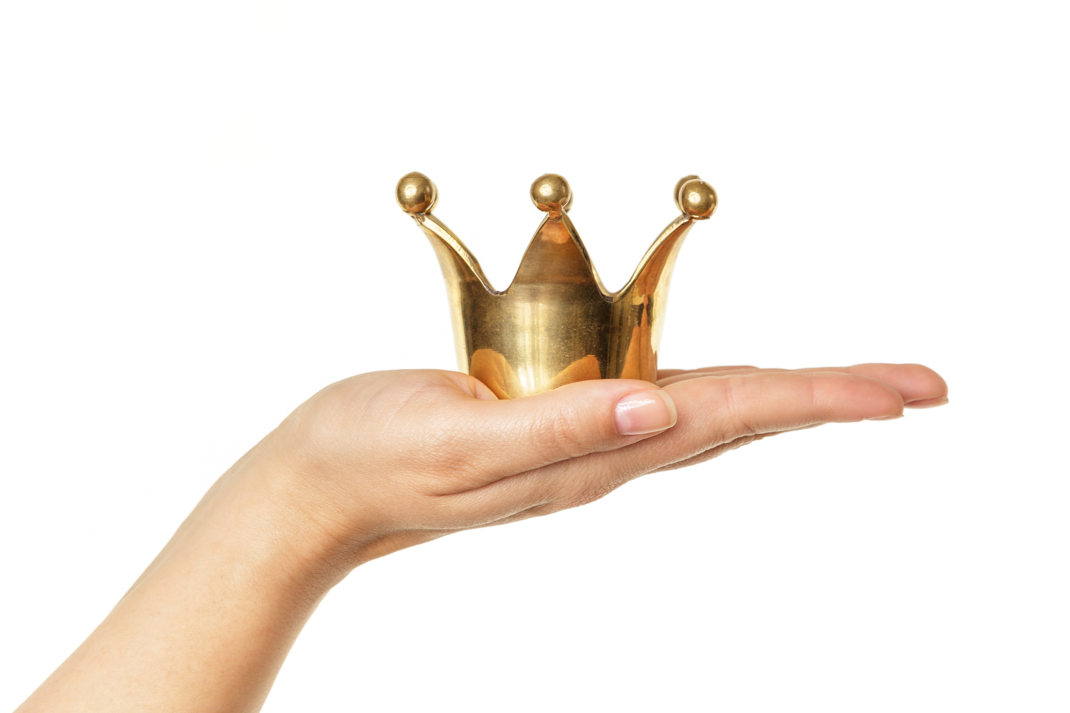 Female hand holding golden crown isolated on white background