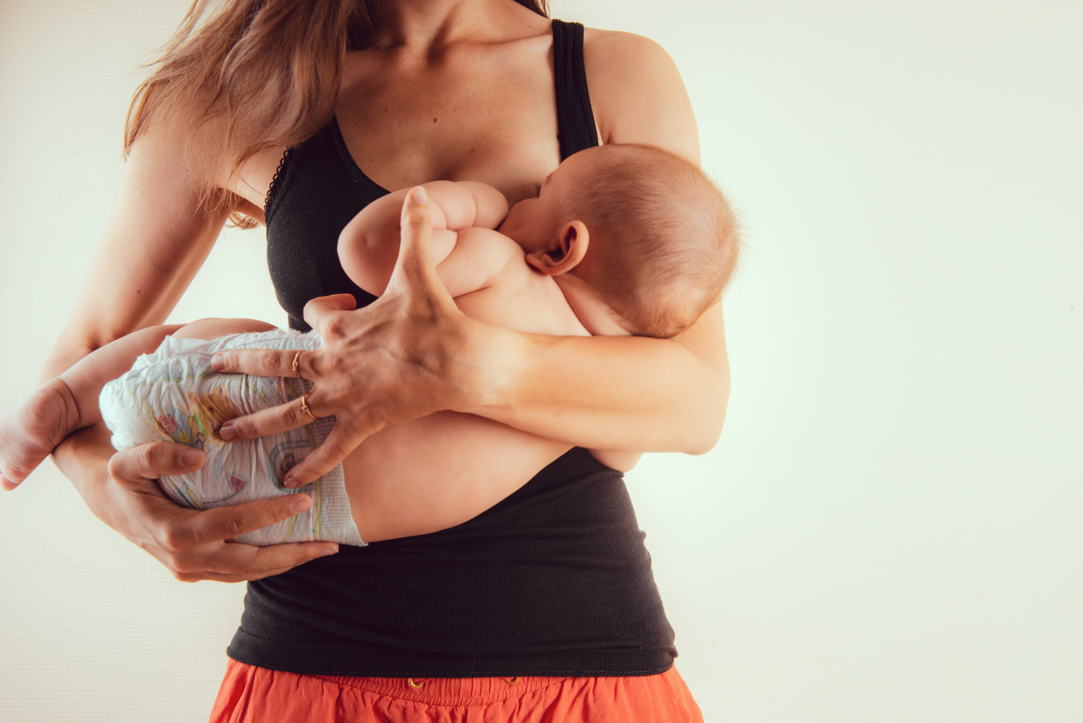 Happy mother with newborn baby infant on hands standing and breasfeeding lacting lactation health and care bonding time