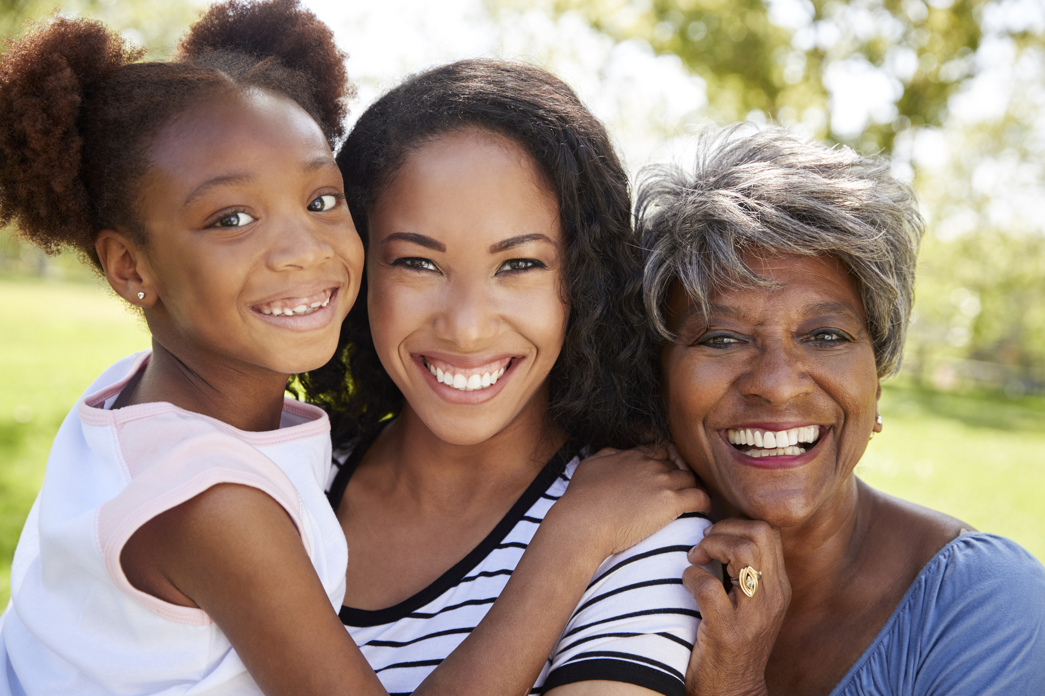 Portrait Of Grandmother With Adult Daughter And Granddaughter Relaxing In Park