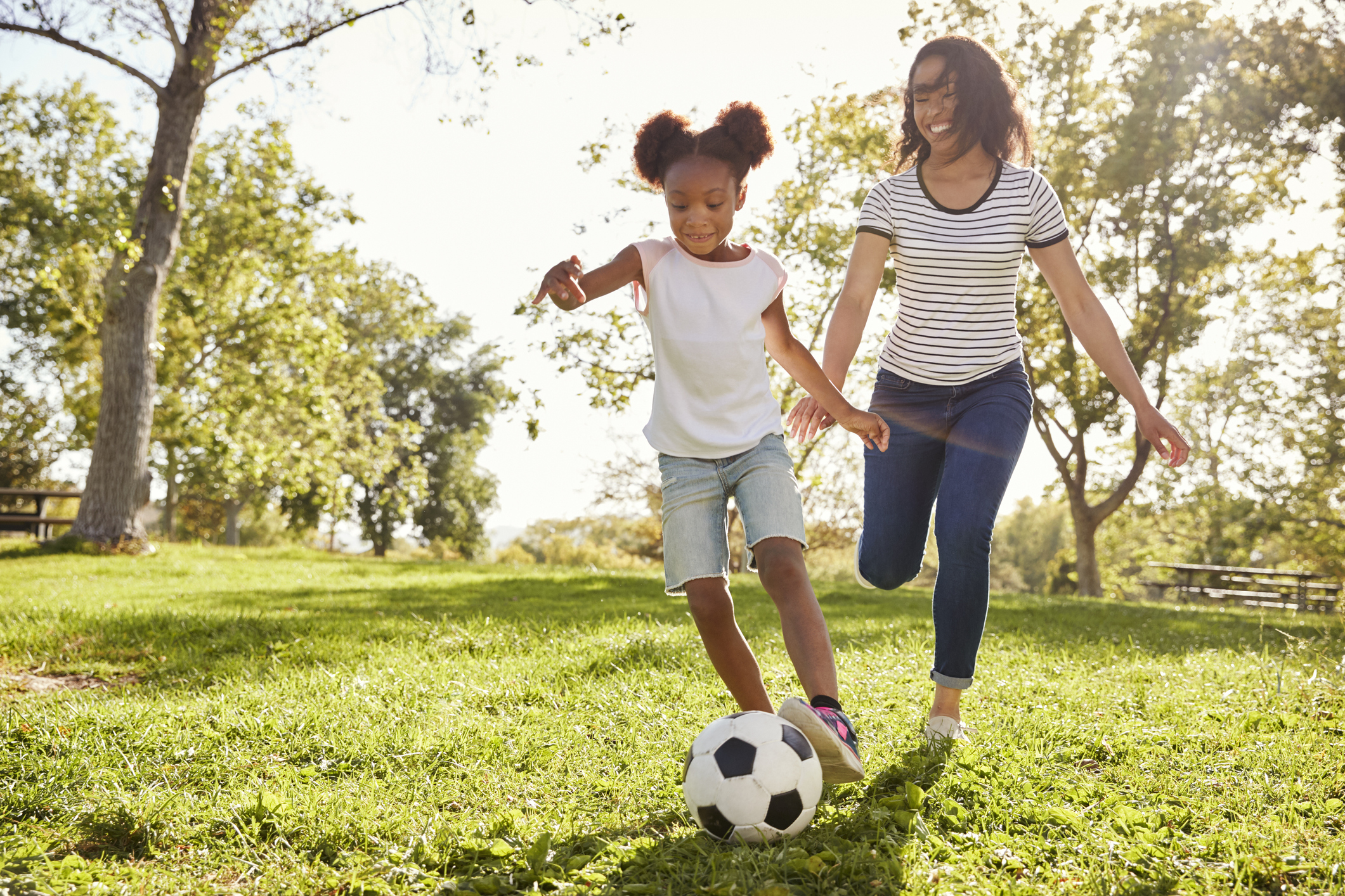 Mother And Daughter Playing Soccer In Park Together