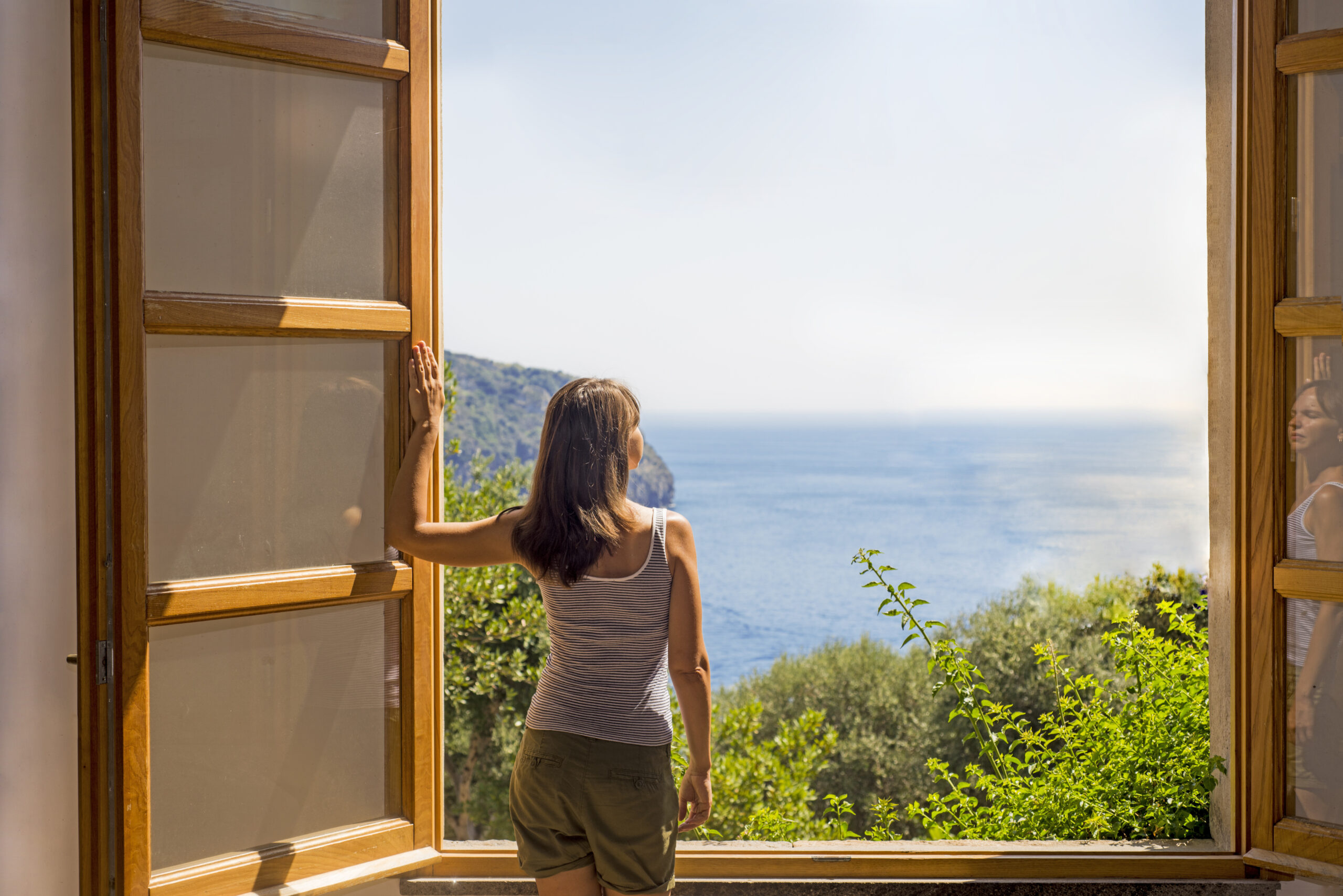 Young woman at a large open window.