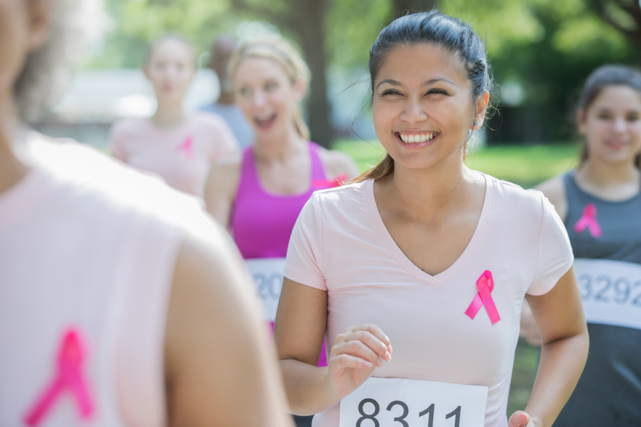 Asian American woman smiles while running charity race to benefit breast cancer research