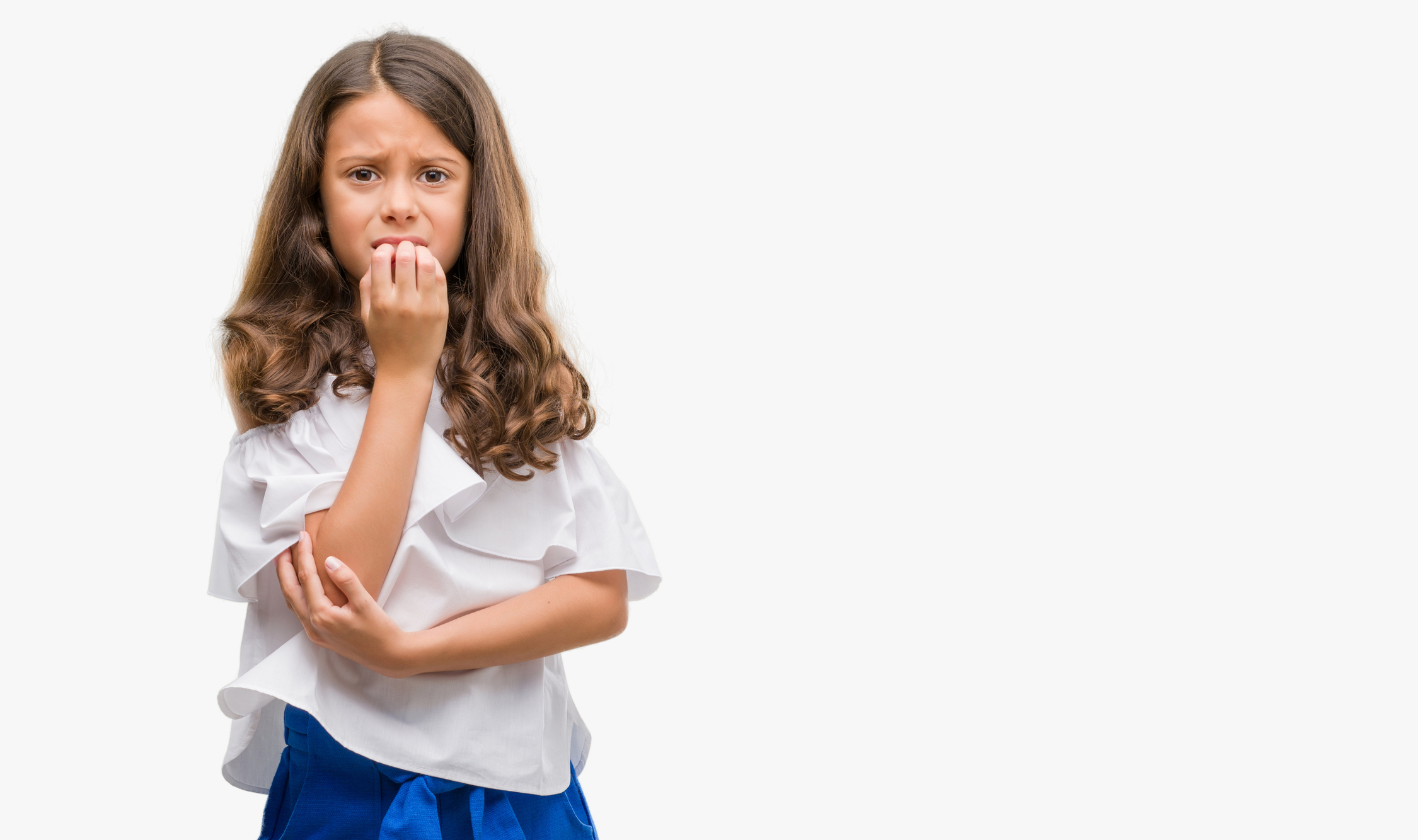 Brunette hispanic girl looking stressed and nervous with hands on mouth biting nails. Anxiety problem.