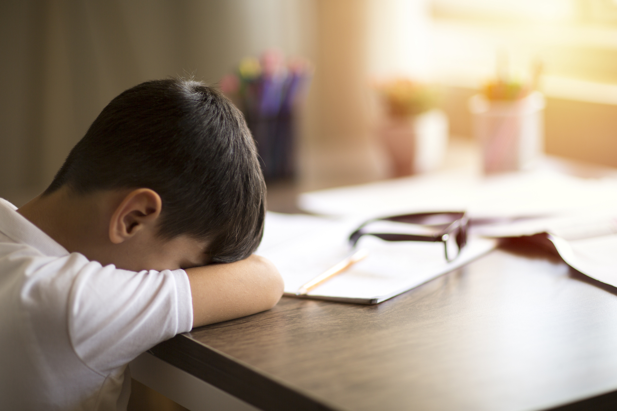 Tired 8 years old boy doing his homework at the table