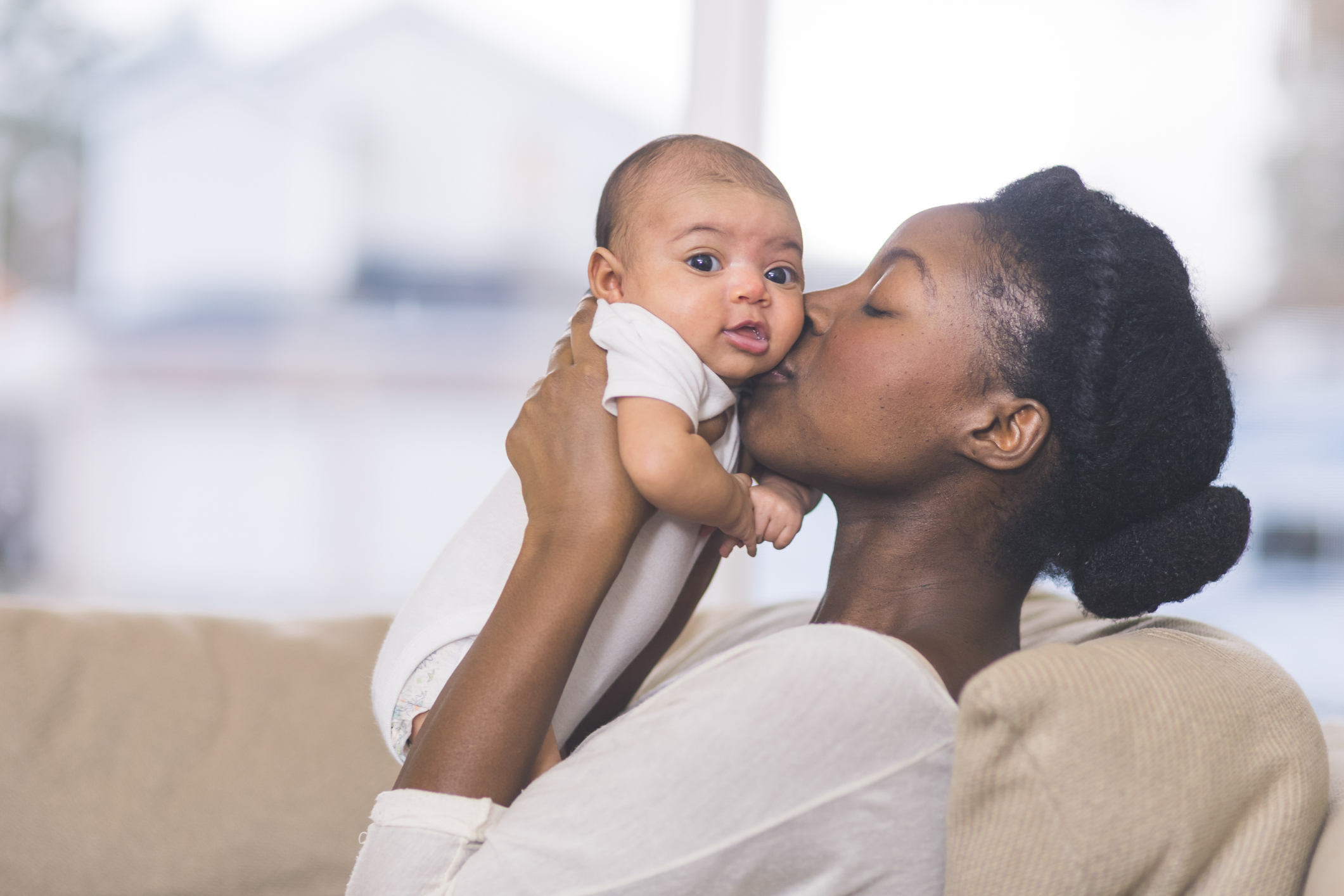 Beautiful African American mother holds newborn baby in the living room