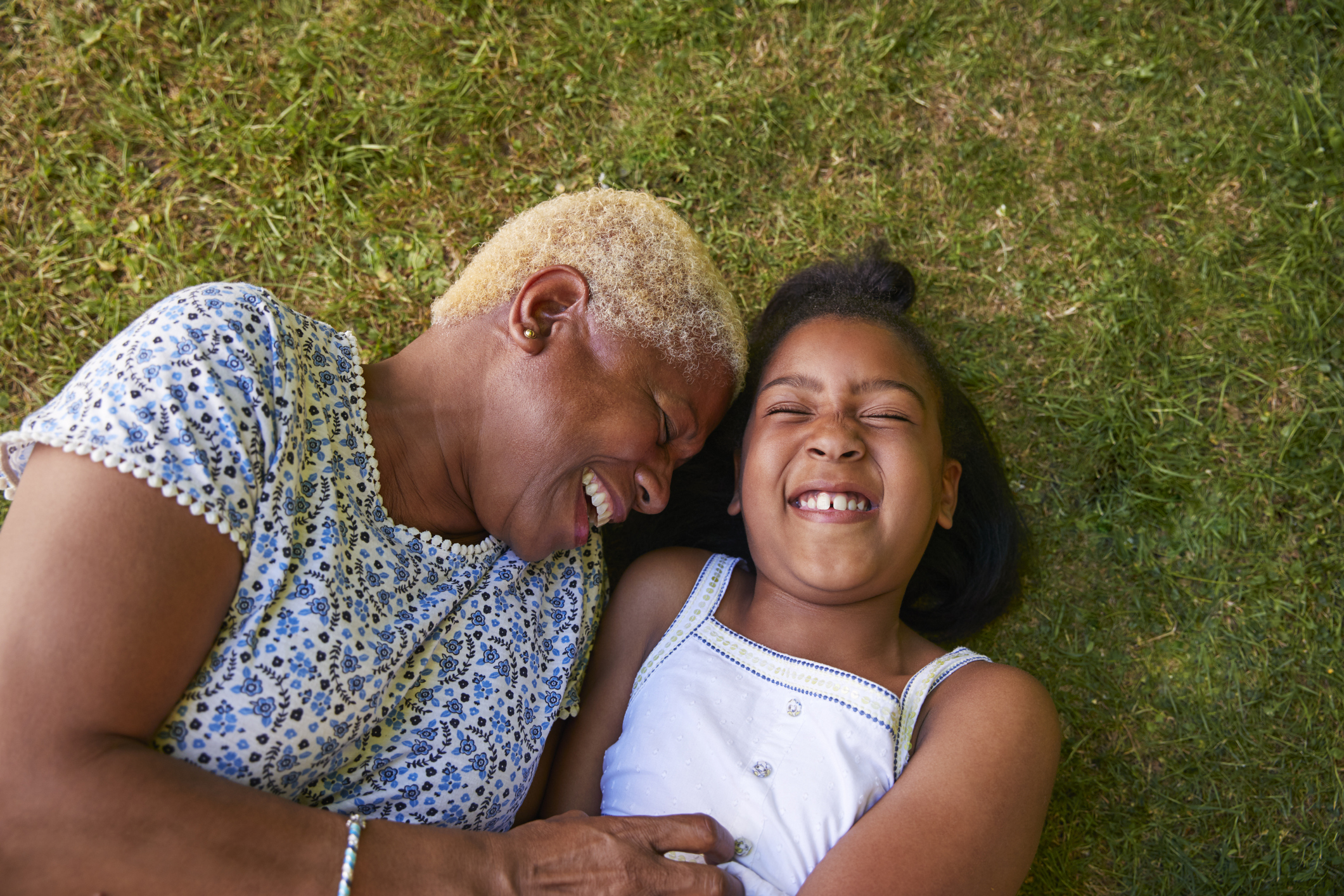 Black girl and grandmother lying on grass, overhead close up