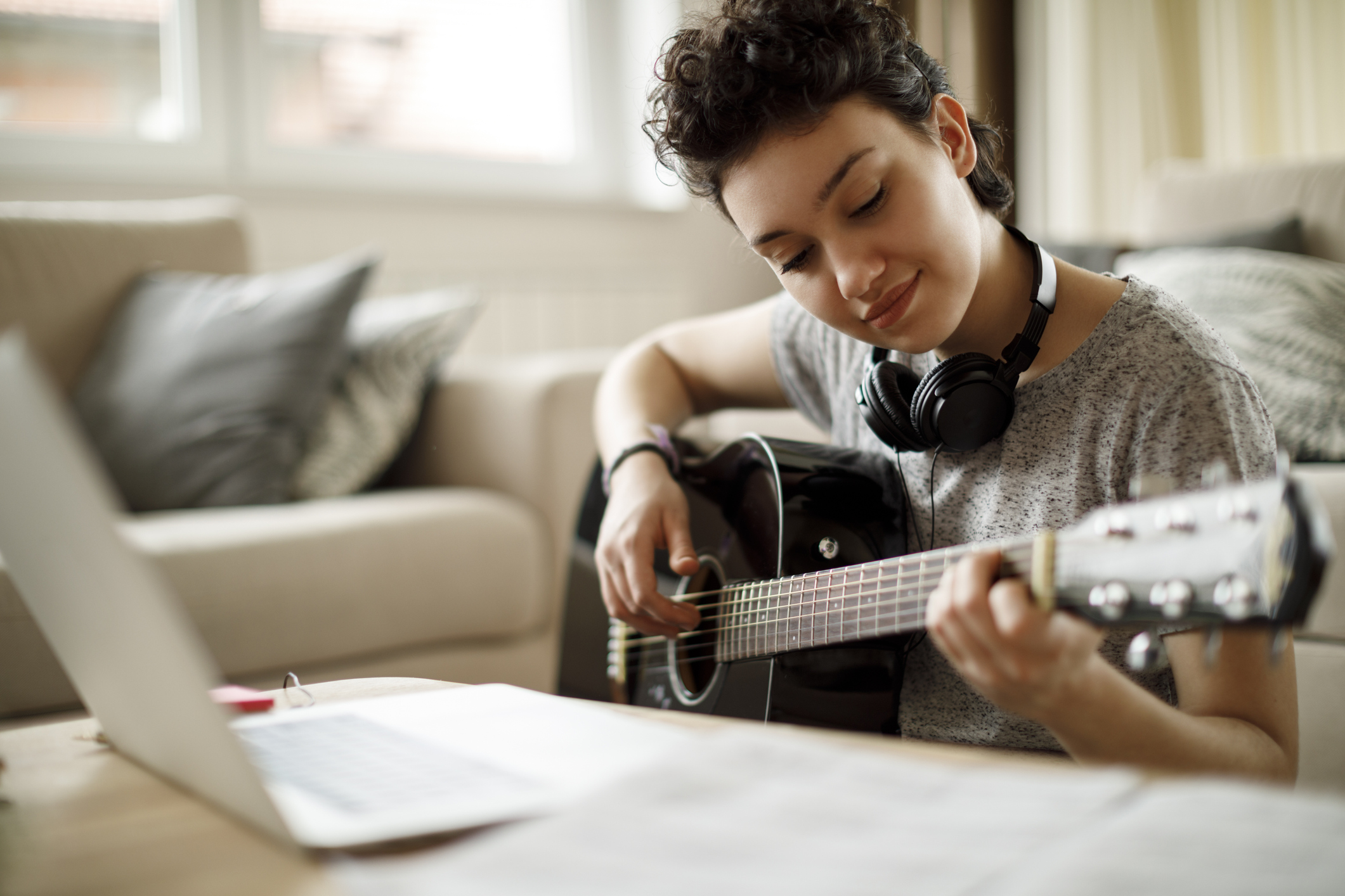 Smiling girl playing a guitar at home