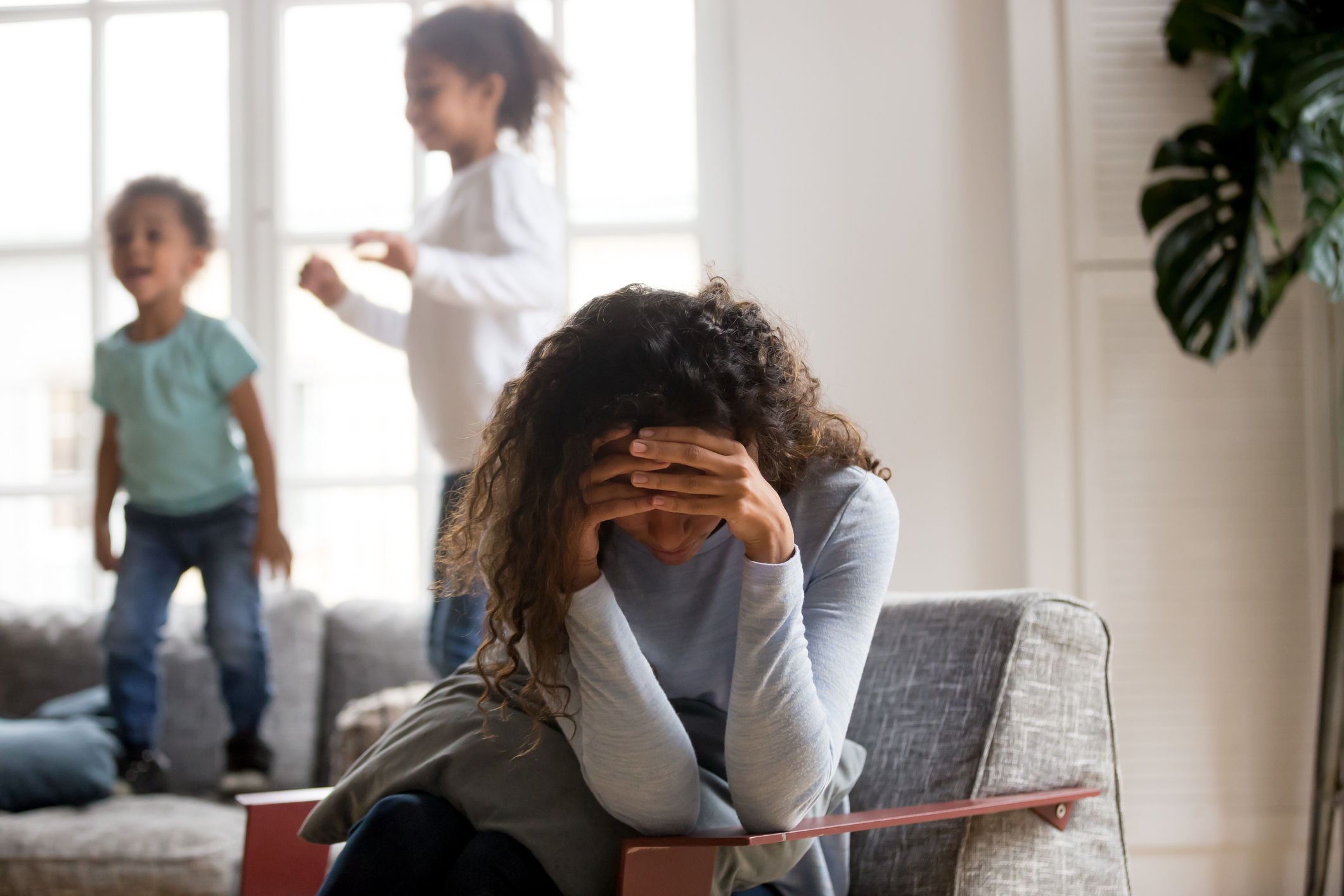 Sad mother and playful children at home