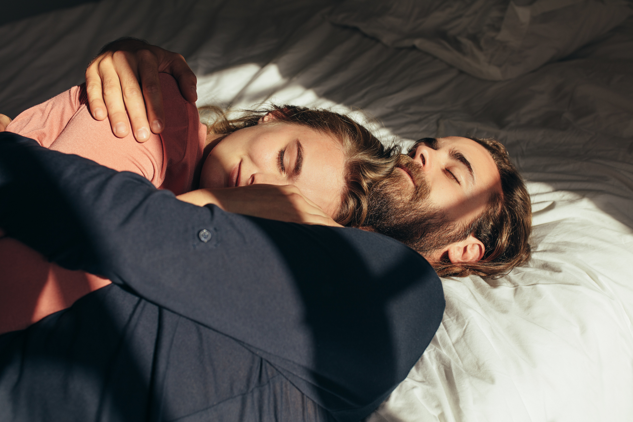 Happy couple sleeping in bed together holding each other