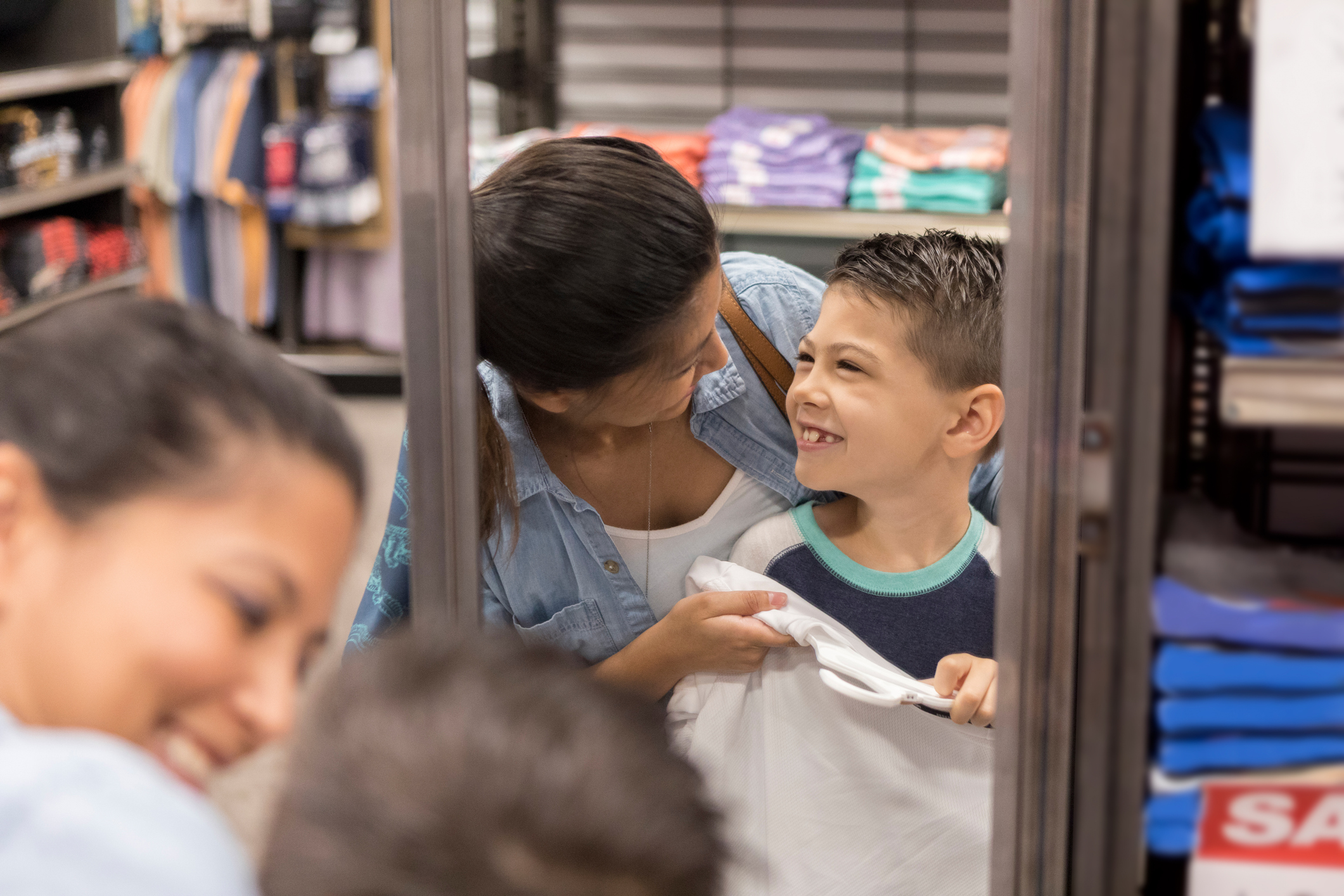 A mother helps her son choose new clothes