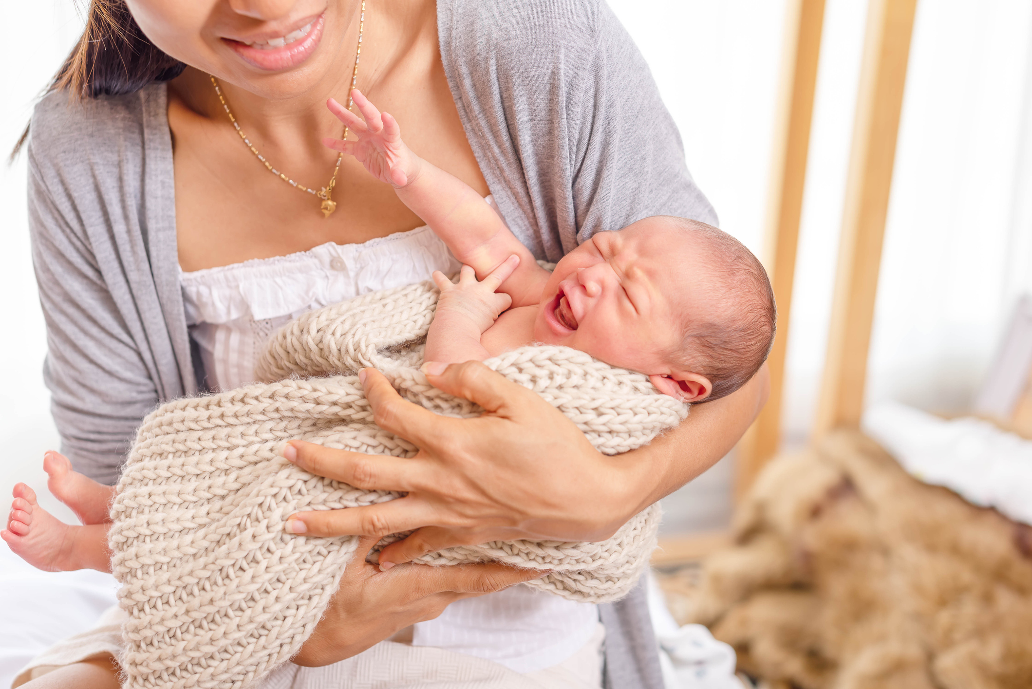 Baby crying in mother arms. Mother hug her little daughter while crying.