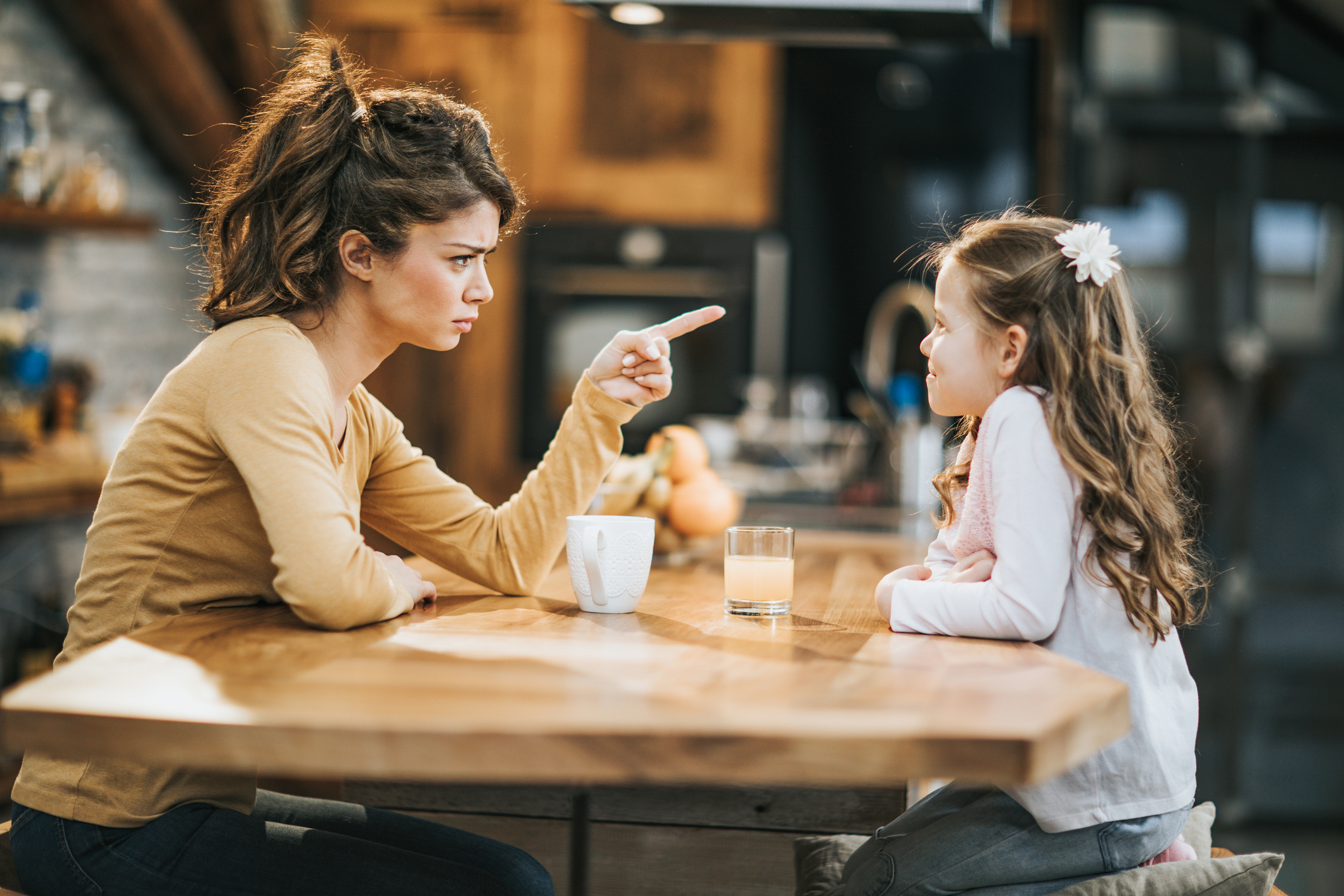 Young mother scolding her little daughter at home.