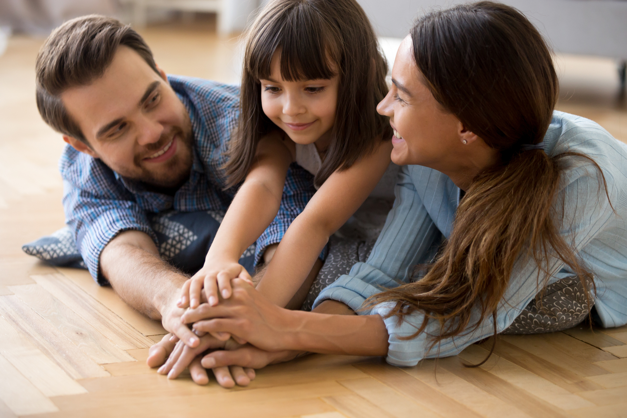 Diverse family lying on warm floor holding hands