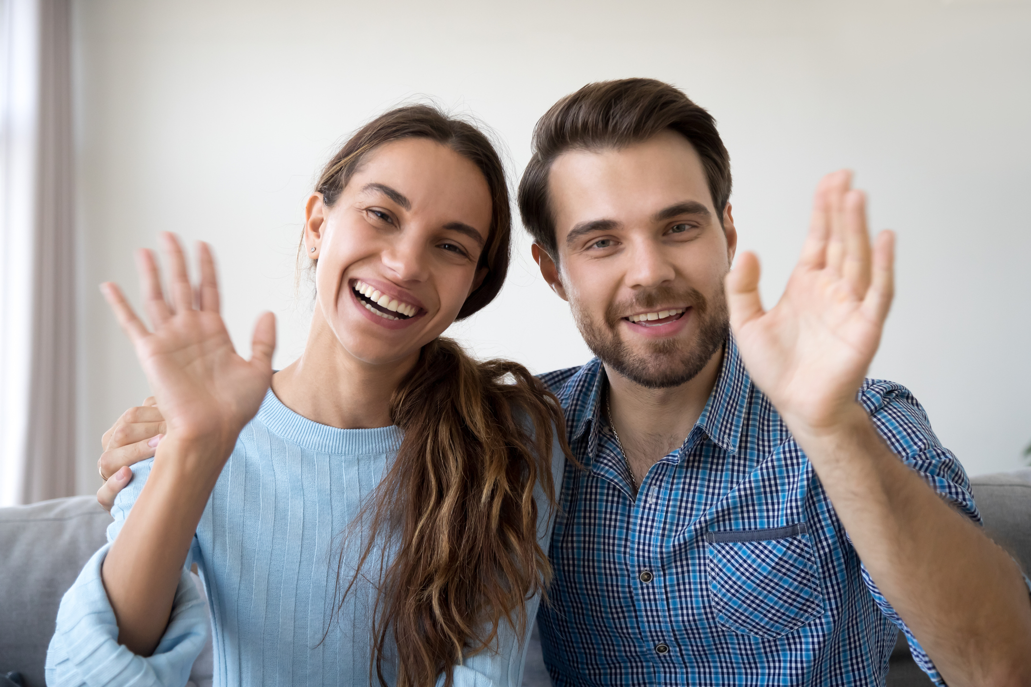 Head shot woman and man waving hands looking at camera