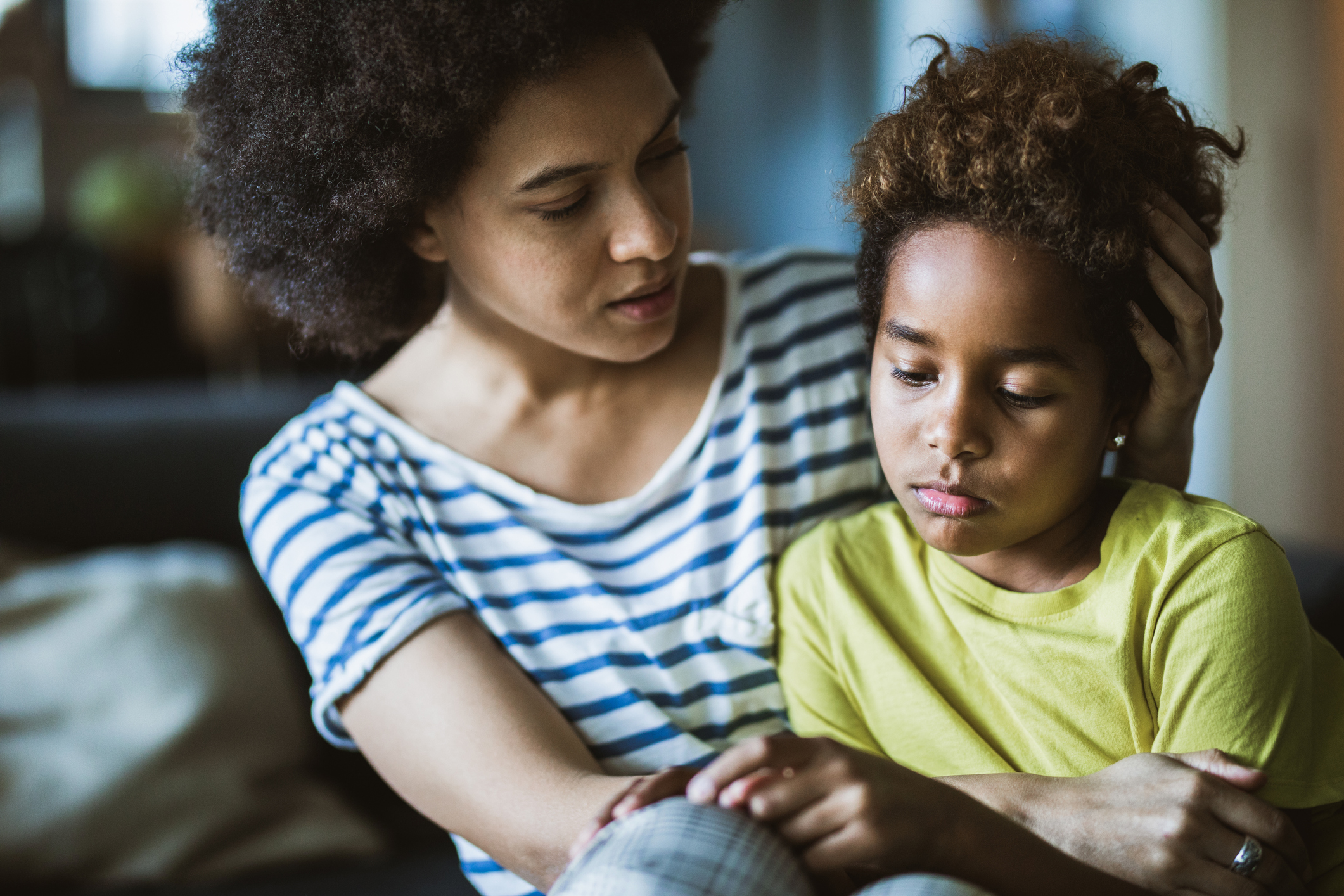 African American mother consoling her sad girl at home.