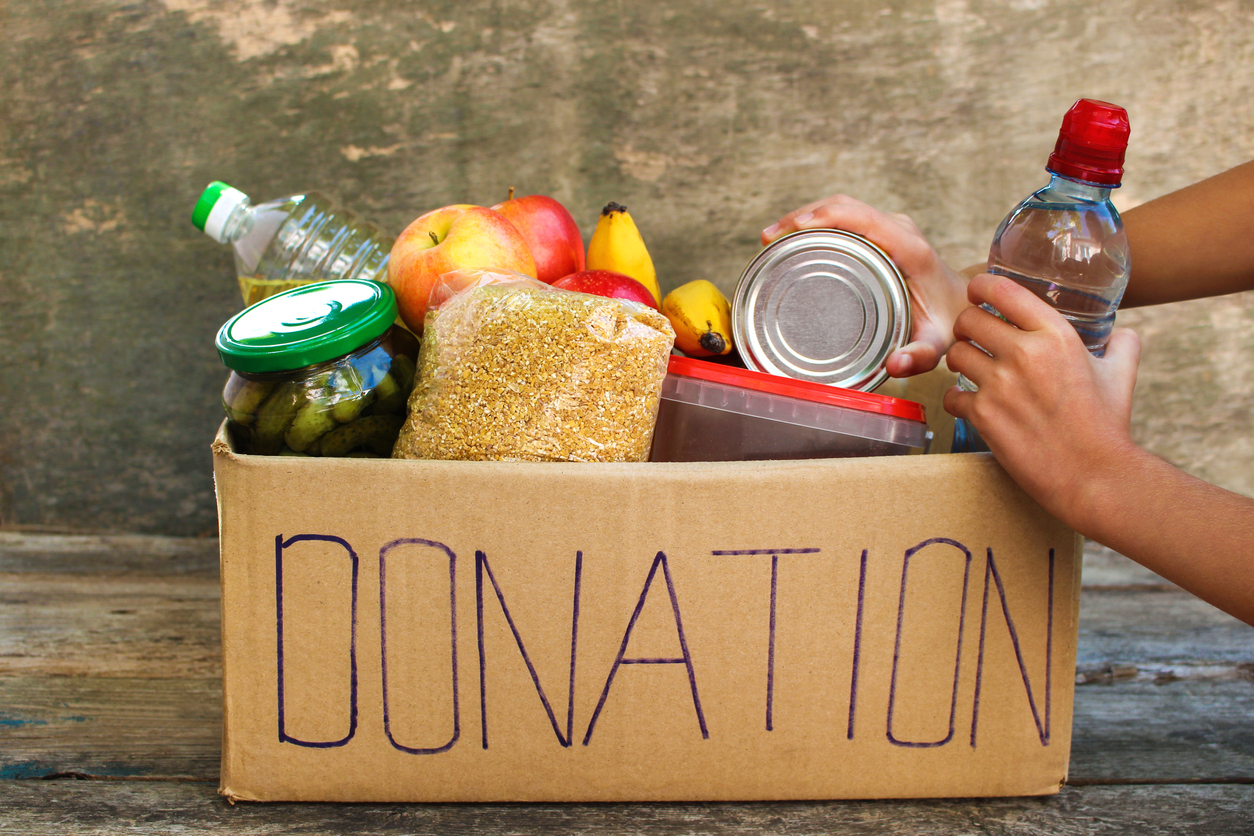 Donation box with food on old wooden background.