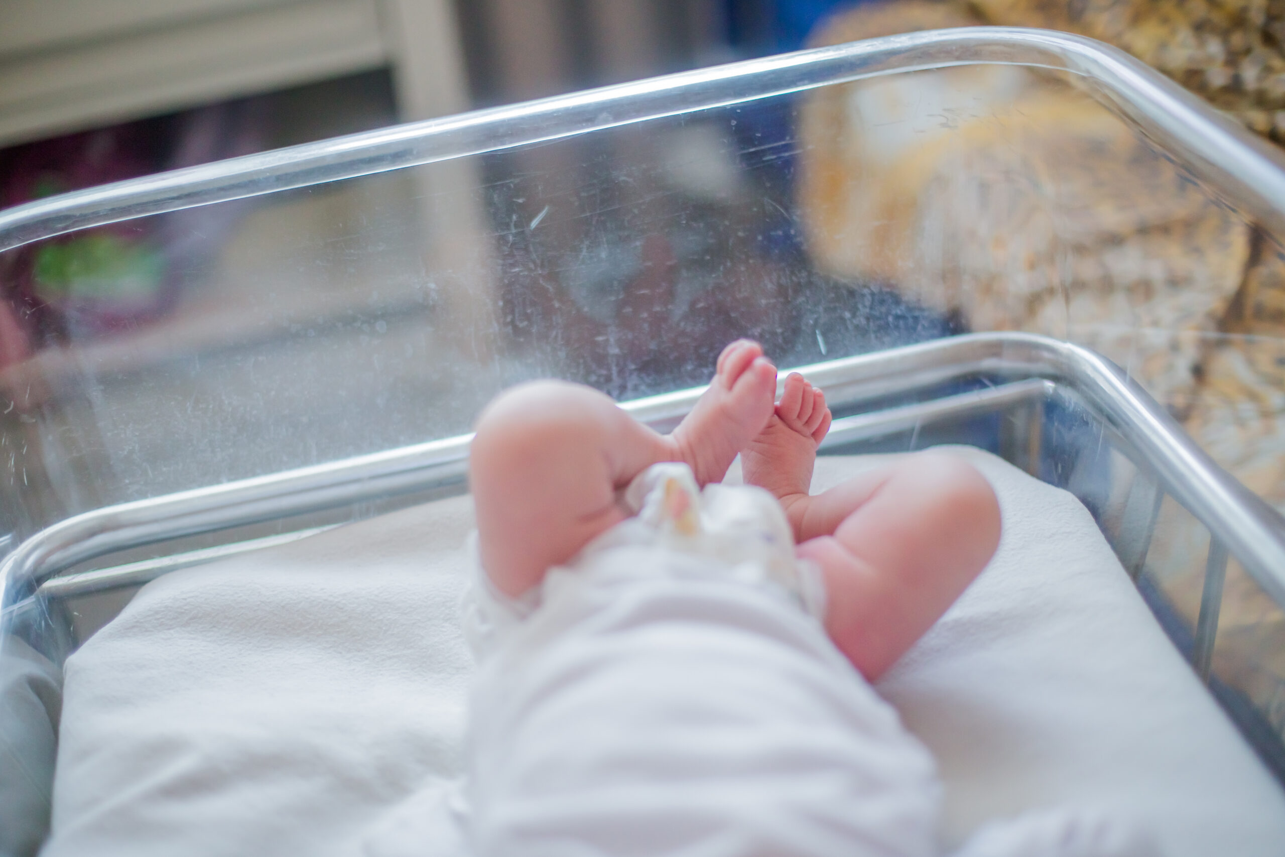 Legs of a newborn baby lying in a couveuse. The child has just been born and is in the hospital clinic with his mother. Natural childbirth. Cesarean section.