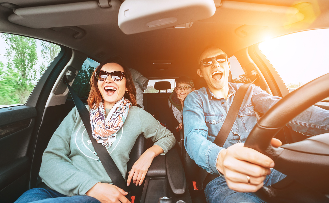 Cheerful young traditional family has a long auto journey and singing aloud the favorite song together.  Safety riding car concept wide angle view image.