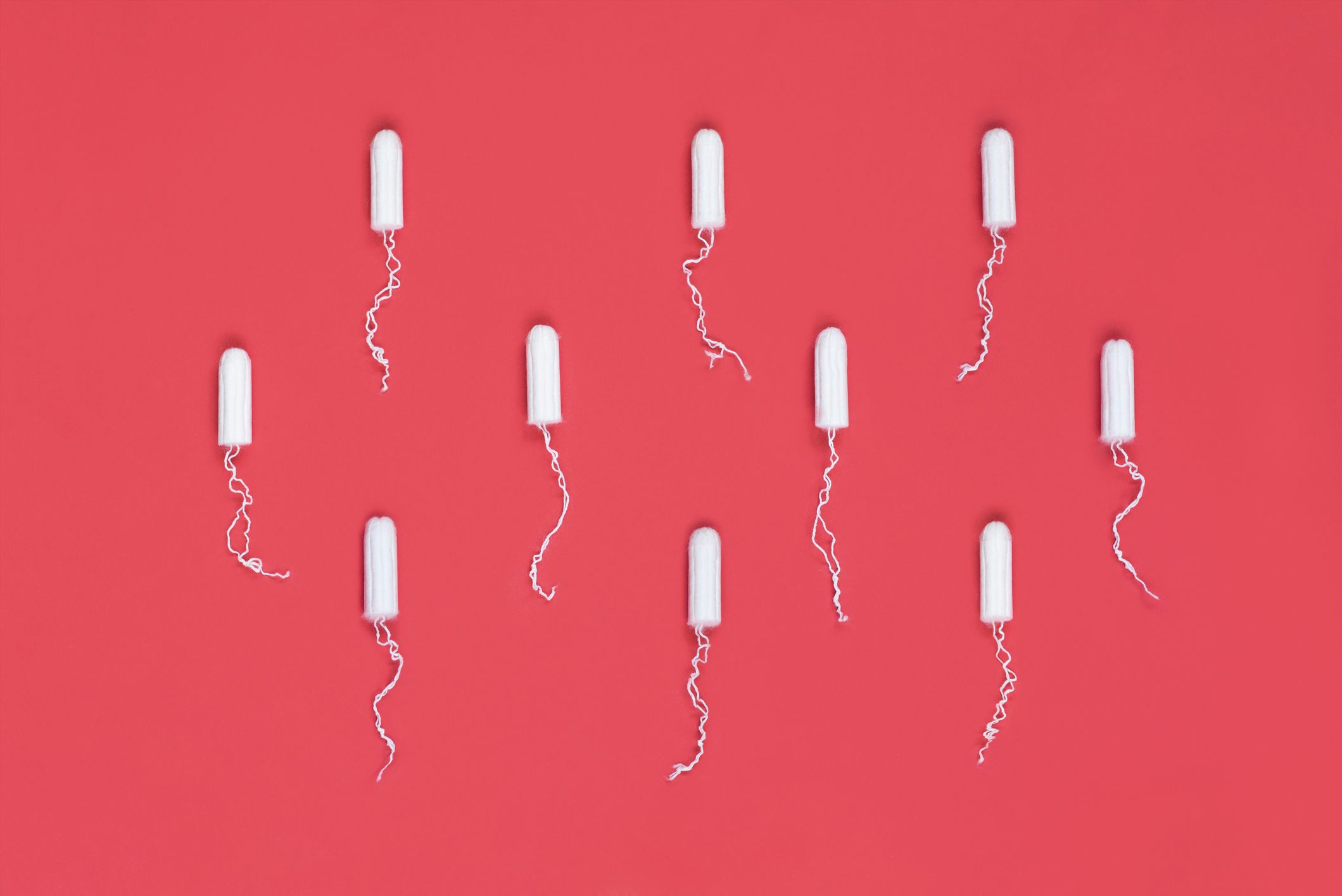 Menstrual period concept. Woman hygiene protection. Cotton tampons on red background. Top view, flat lay.