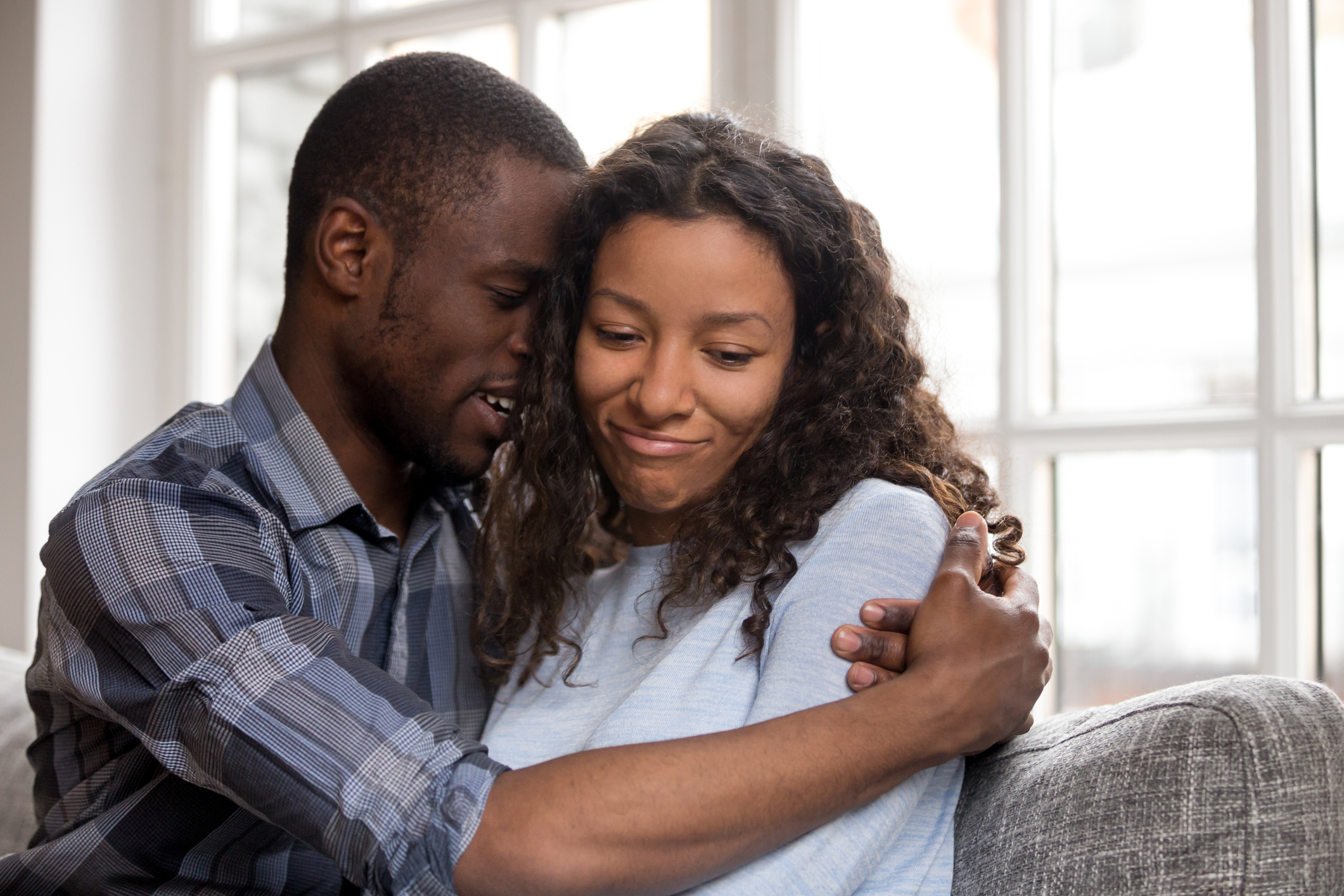 Loving African American husband embracing wife after quarrel