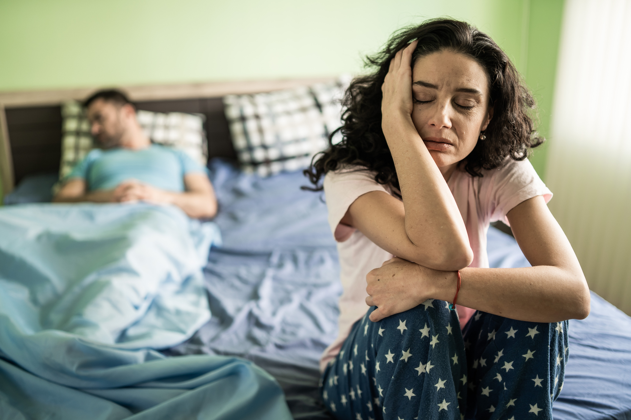 Sad womansitting on bed, hand on head