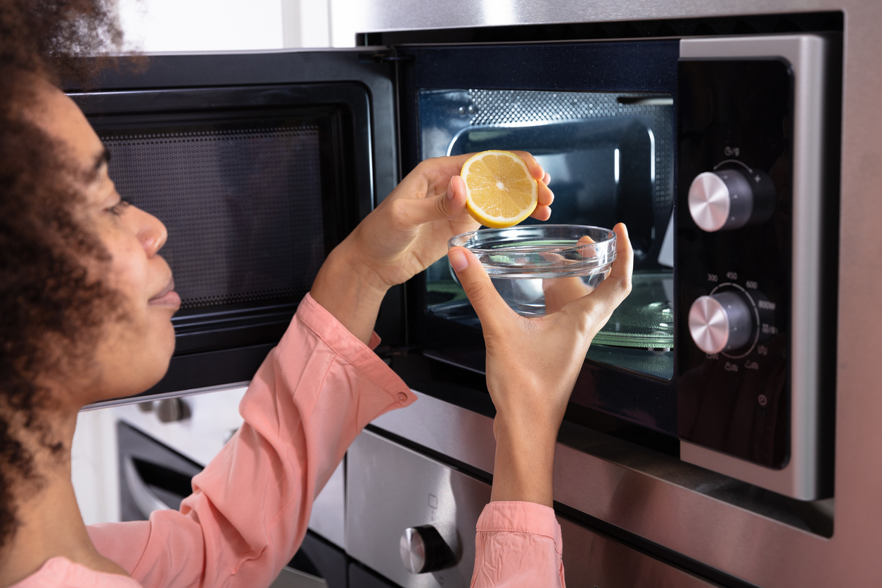 Woman's Hand Squeezing Halved Lemon In Bowl