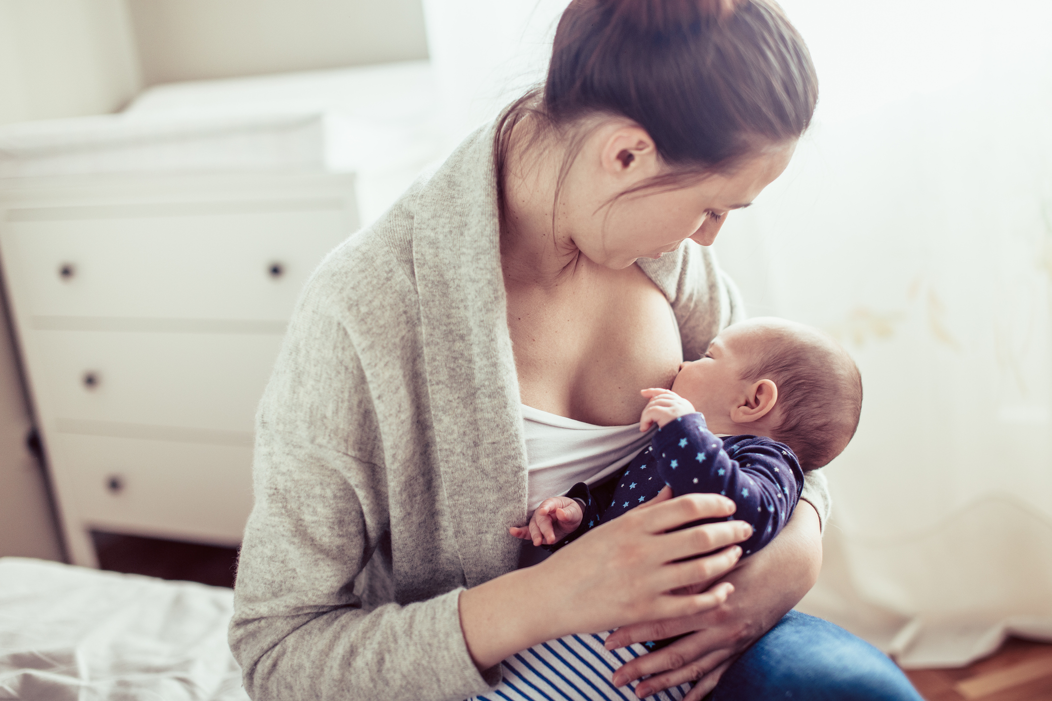 Young mother breastfed her baby girl. Mother breastfed baby at the bedroom.