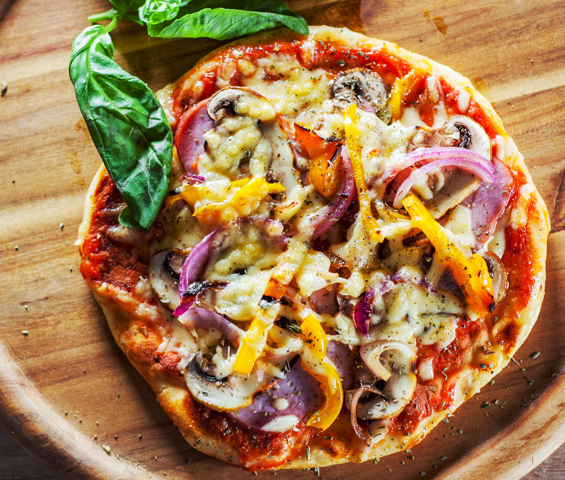 Greek pizza with mushrooms, ham, cheese, onions, pepper on wooden board