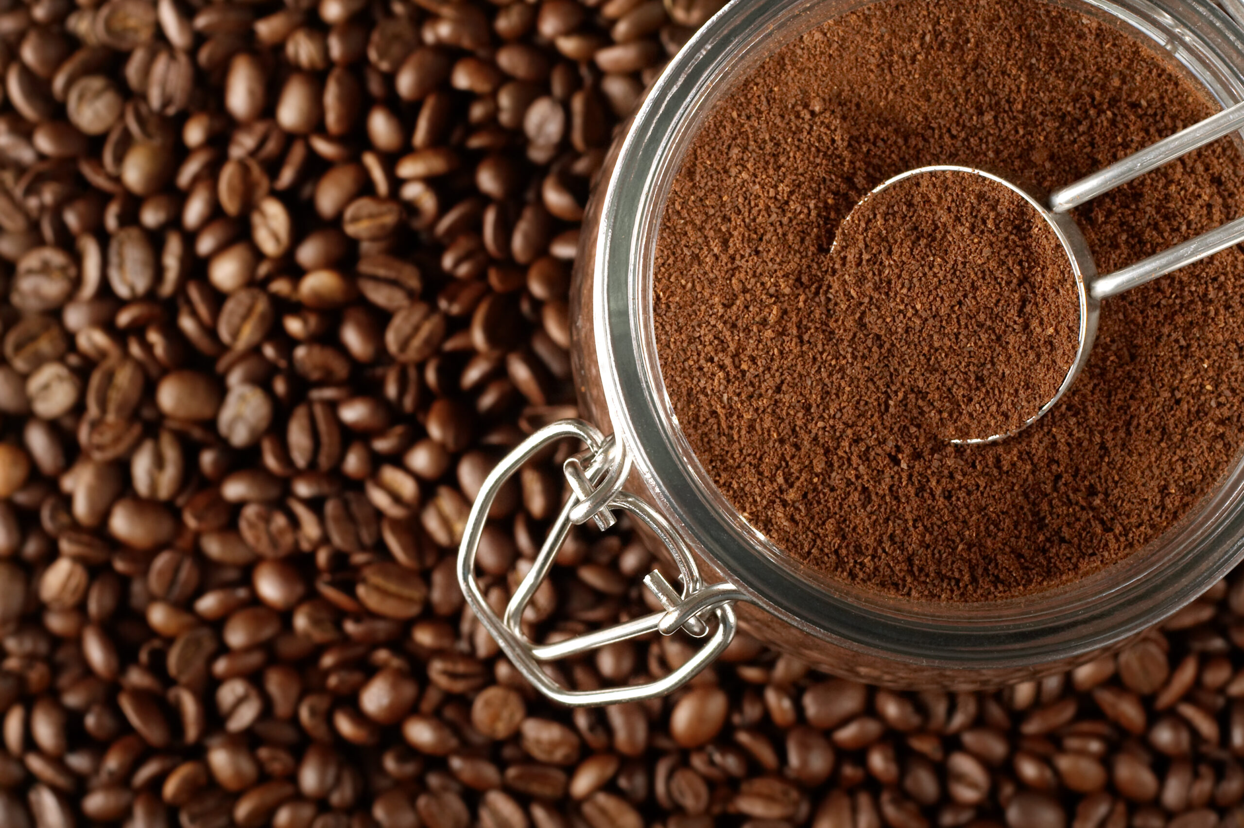 Close up of many whole coffee beans and ground coffee beans