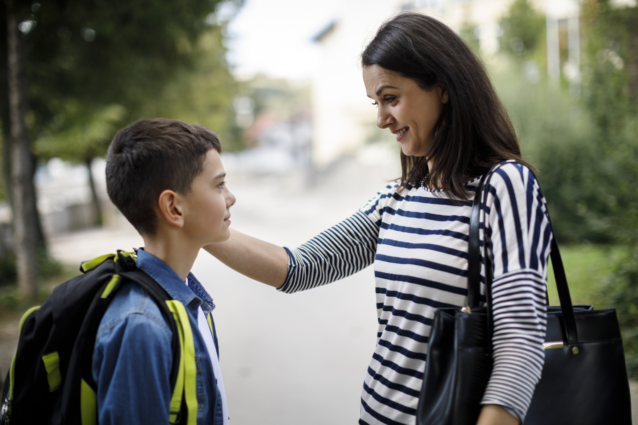 Mother saying goodbye to son in front of school