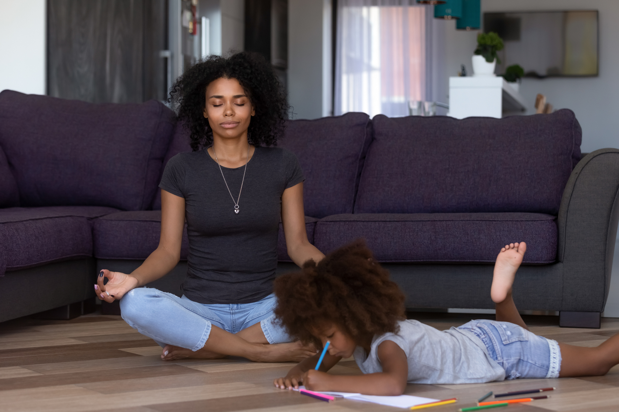 African mom doing yoga while kid daughter drawing on floor