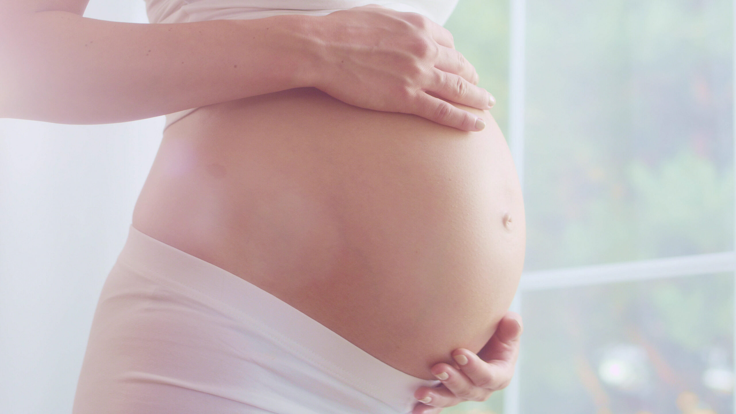 Waiting for a baby. Pregnant woman rubbing her naked belly