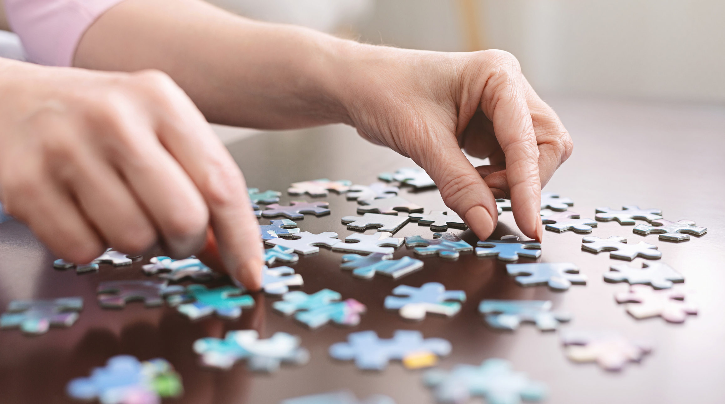 Elderly woman hands doing jigsaw puzzle closeup