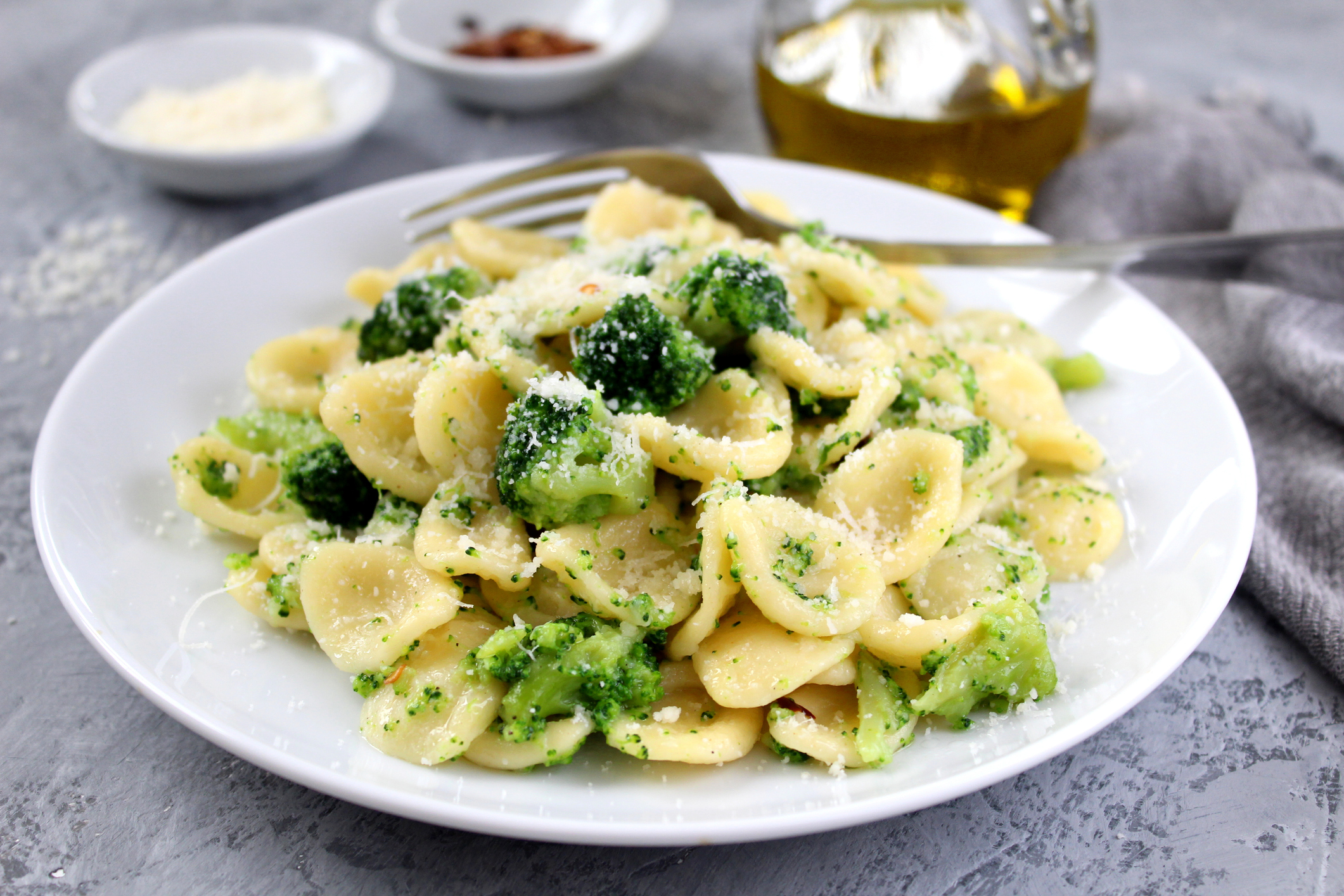 Homemade pasta orecchiette with broccoli, Parmesan cheese and chili pepper on light background.